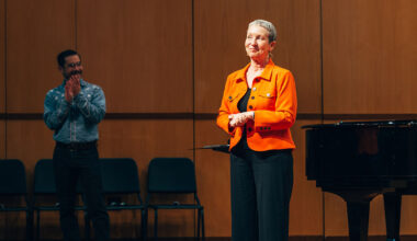 Woman stands centerstage as student applauds.