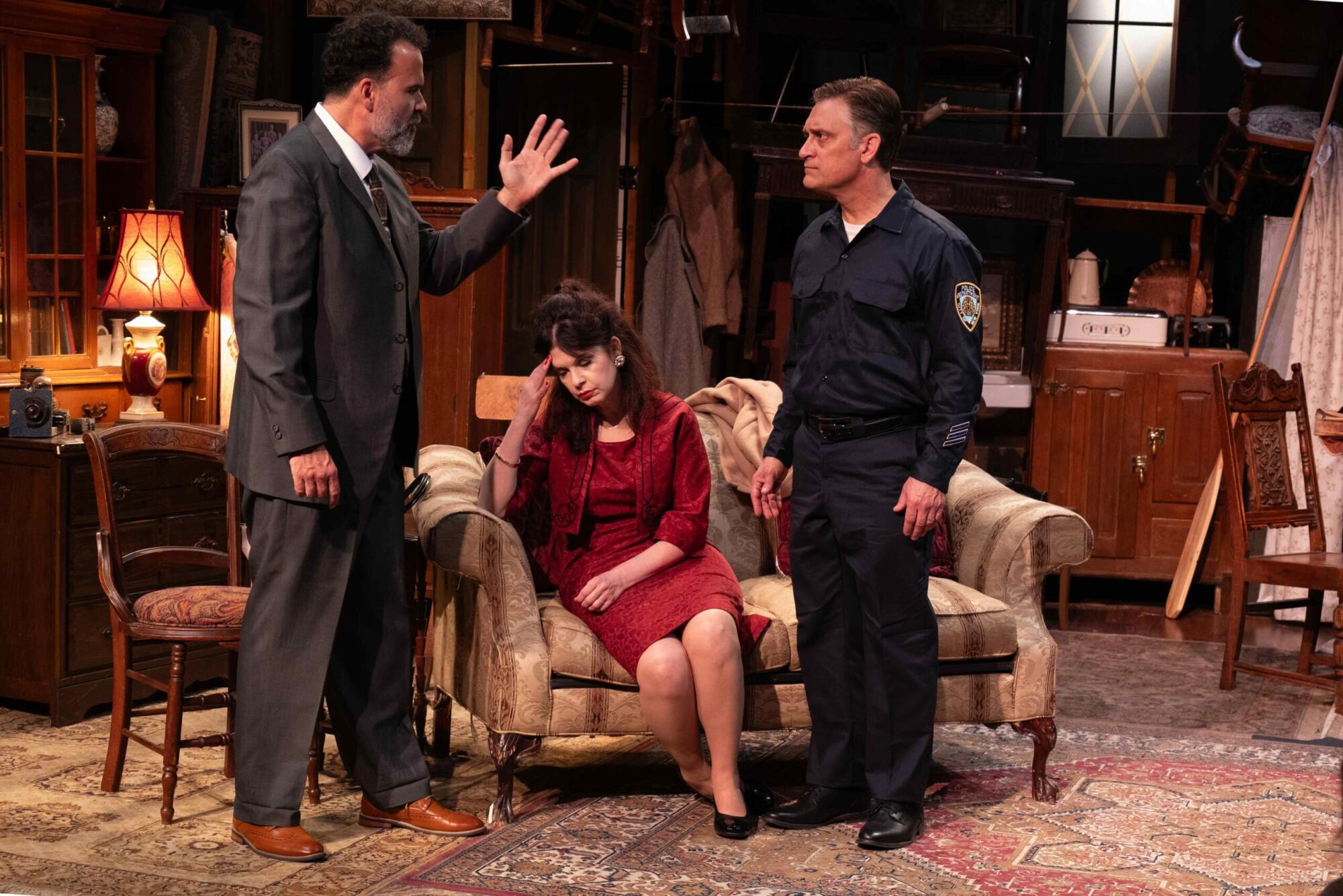Jason Huber, Dana Dewes and Scott G. Jackson stand in a living room in "The Price."
