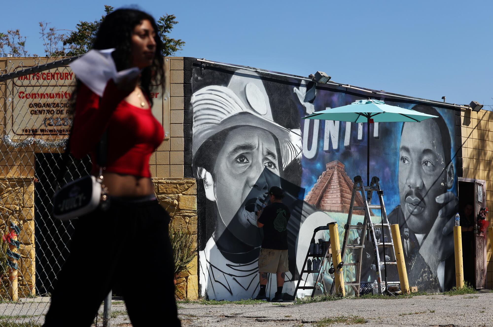 Mural artist MisterAlek replaces a portrait of Cesar Chavez that he created in 2021 with a portrait of Delores Huerta.