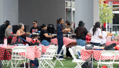 several people standing at a serving table getting good
