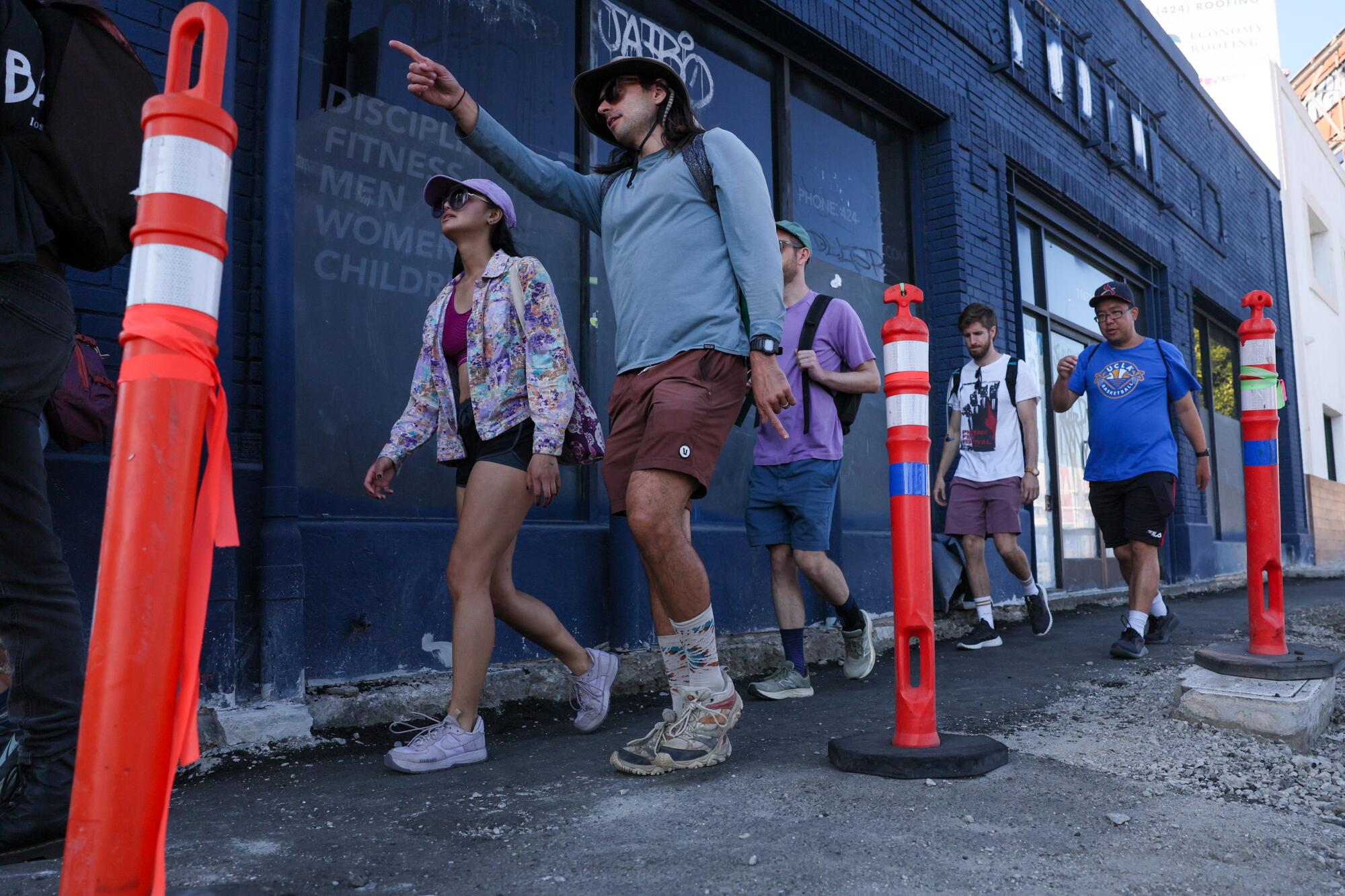 Walkers pass by construction zone cones on the sidewalk.