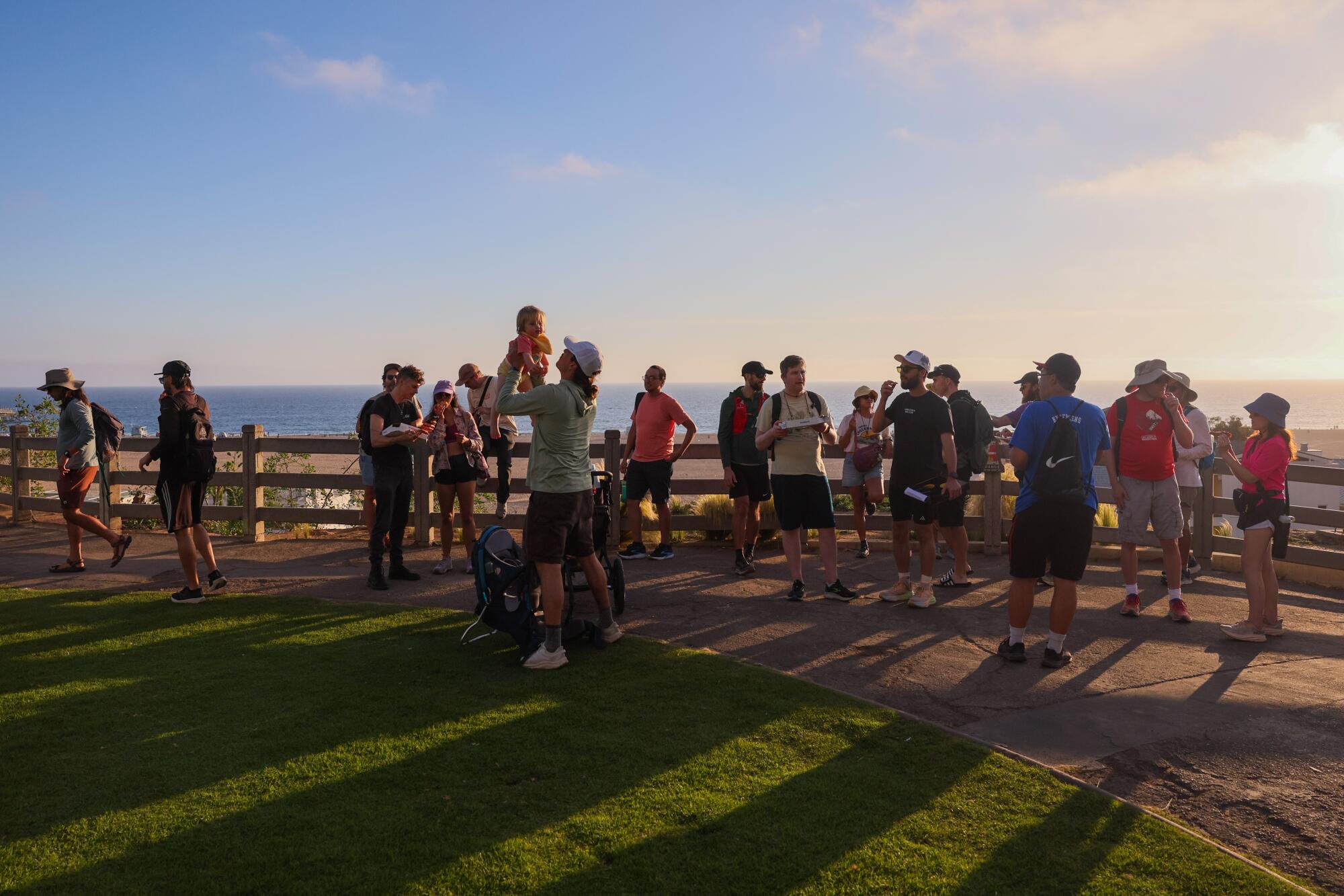 People gather at a railing overlooking the ocean.