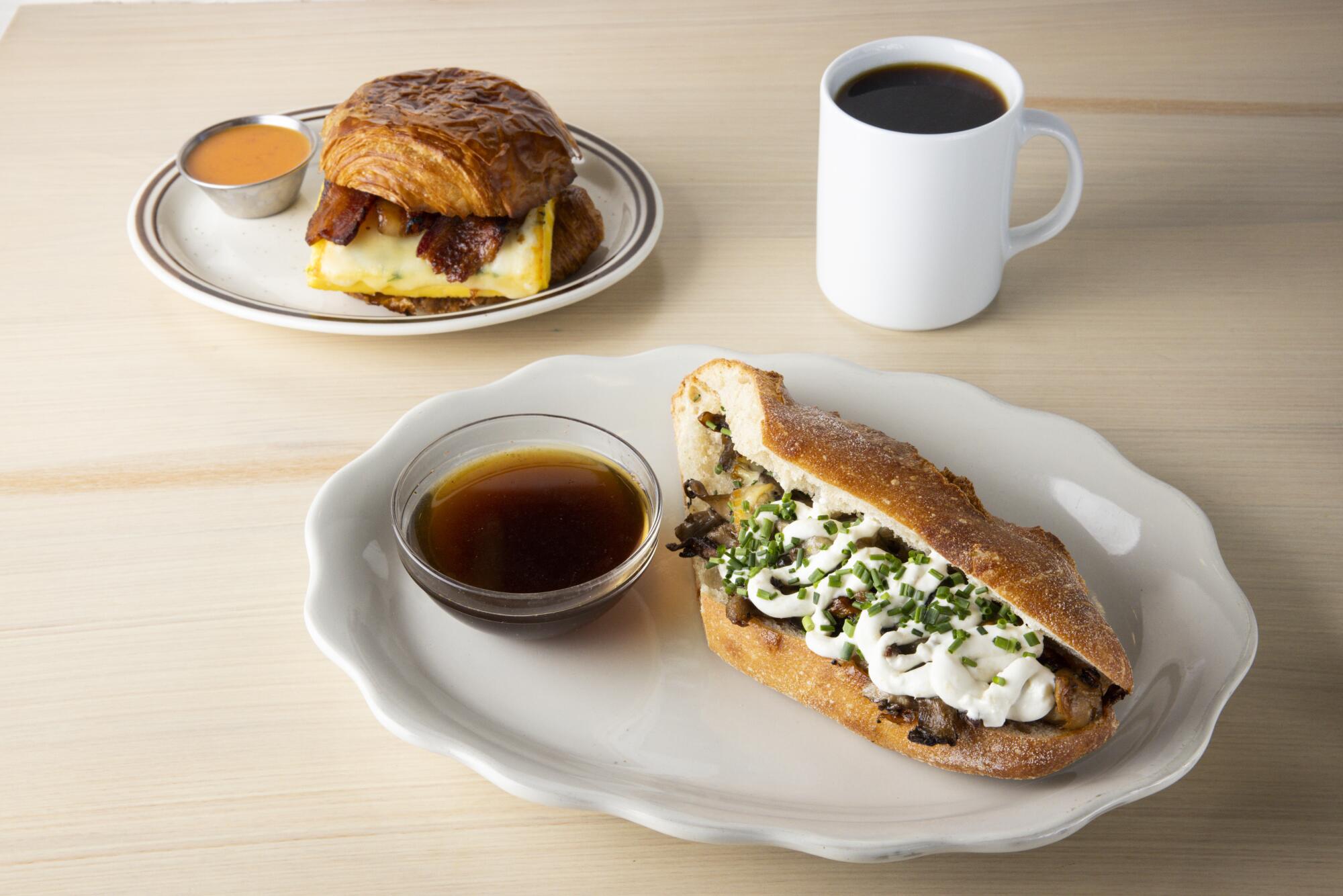 The croissant breakfast sandwich with a side of sweet potato hot sauce, left, and a mushroom dip sandwich.