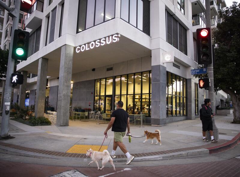 Pedestrians walk past Colossus Harbor in San Pedro. 