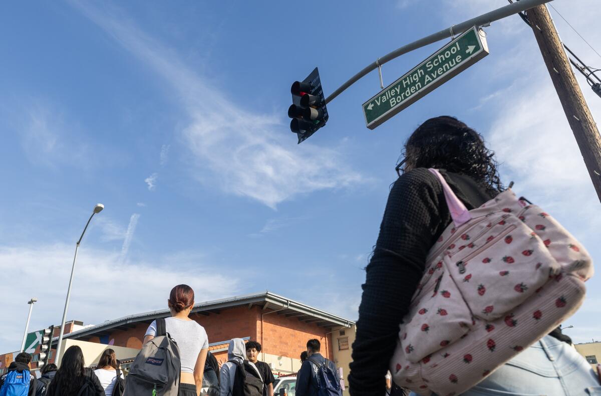 People, some with backpacks, walking under a street light toward a building