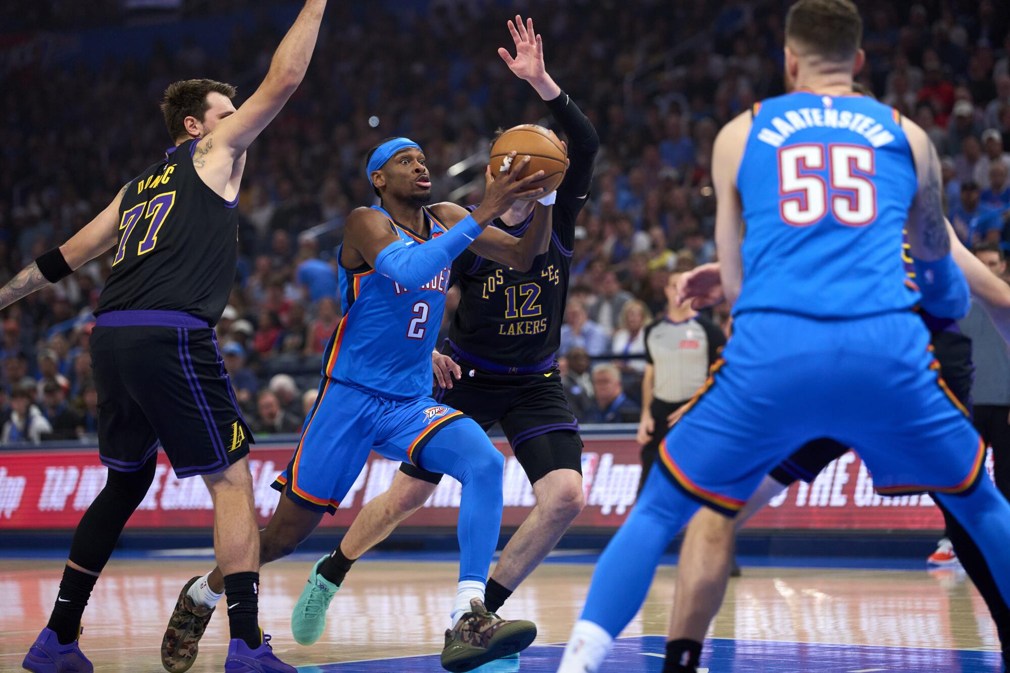 Oklahoma City star Shai Gilgeous-Alexander, center, drives past Lakers star Luka Doncic during the first half Thursday.