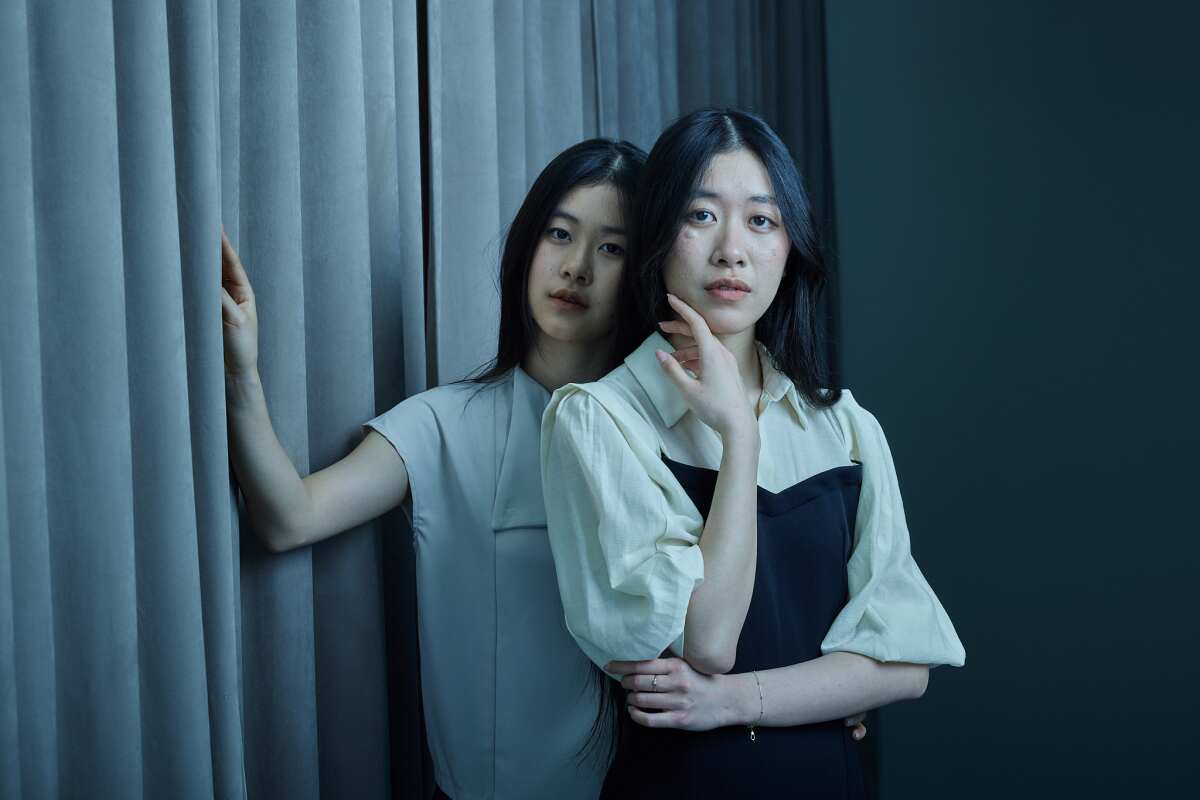 Two women by a curtain.