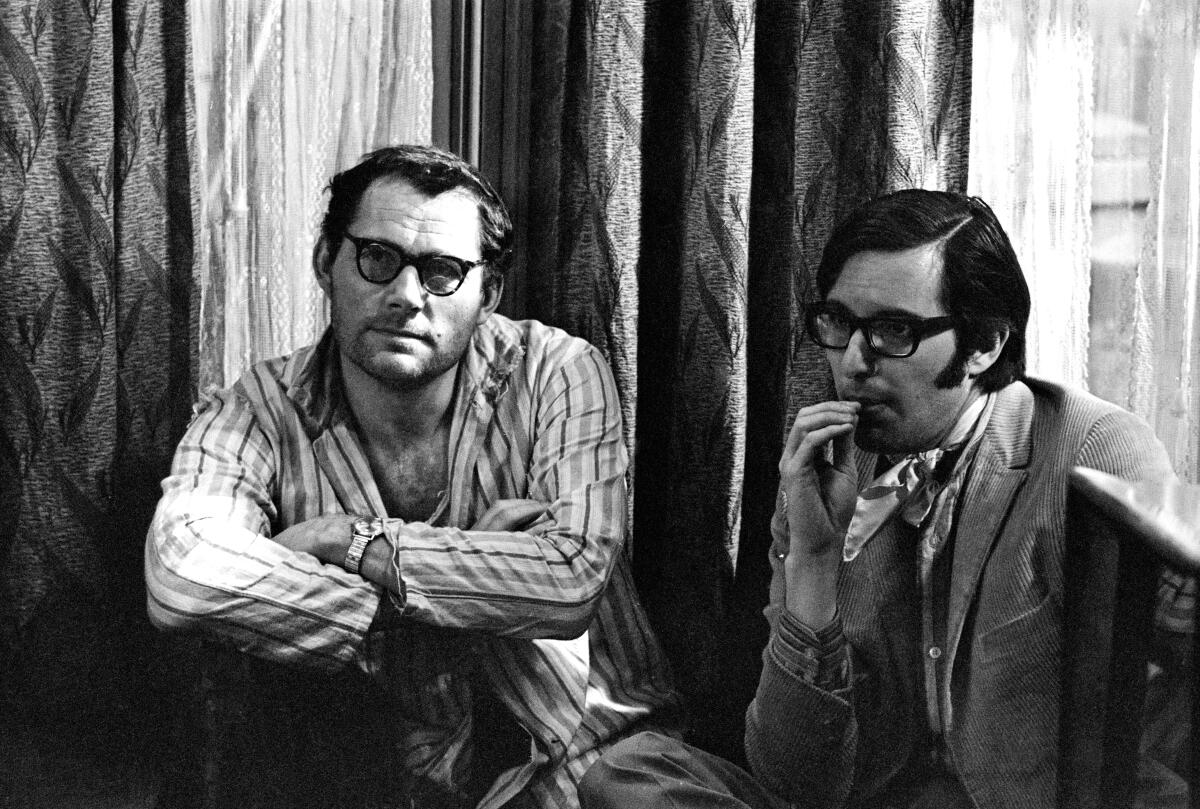 An actor sits with a director on set in conversation.