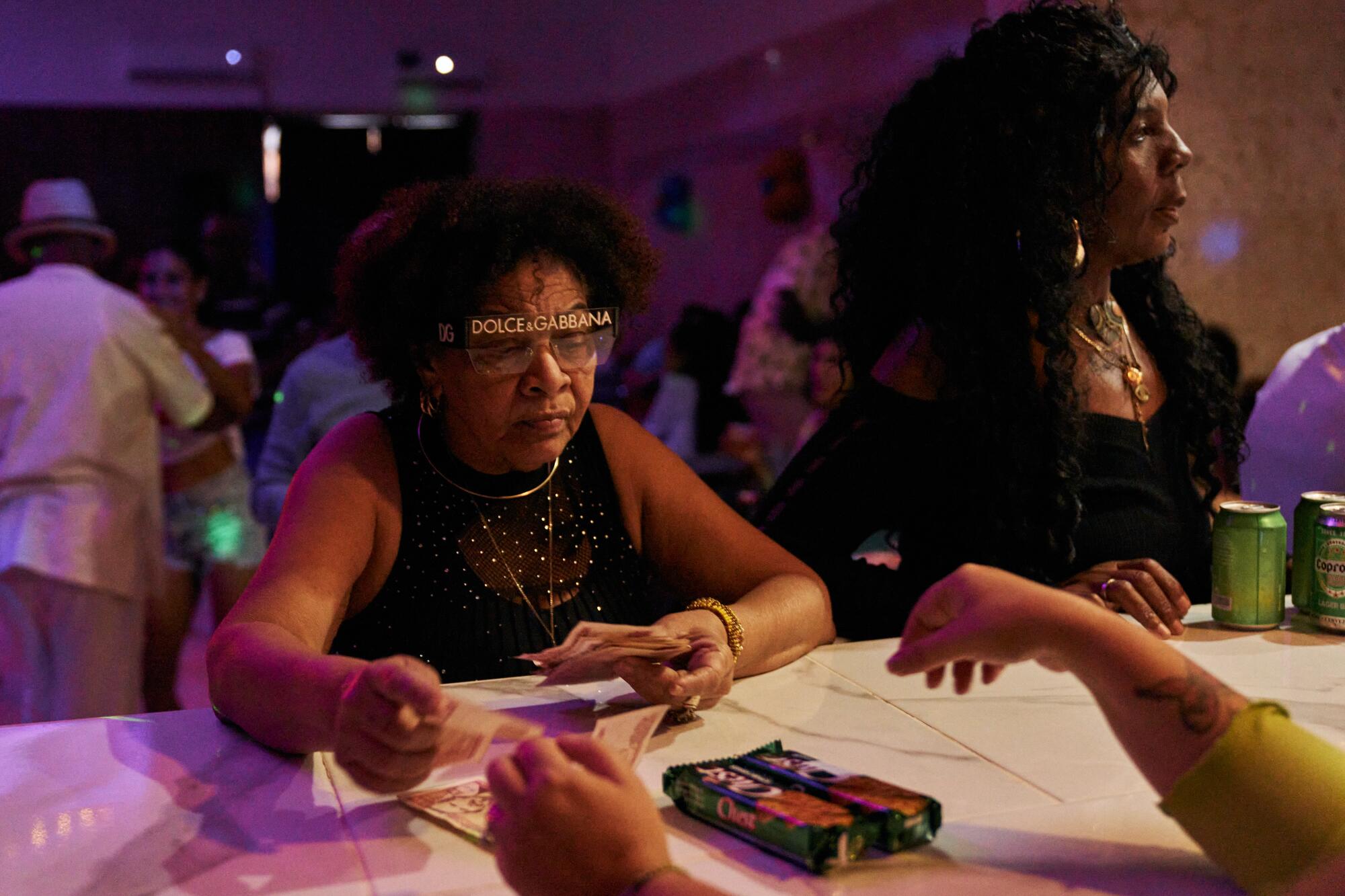 María Camejo pays for cookies at the bar during the "Los Tradicionales" gathering in Havana