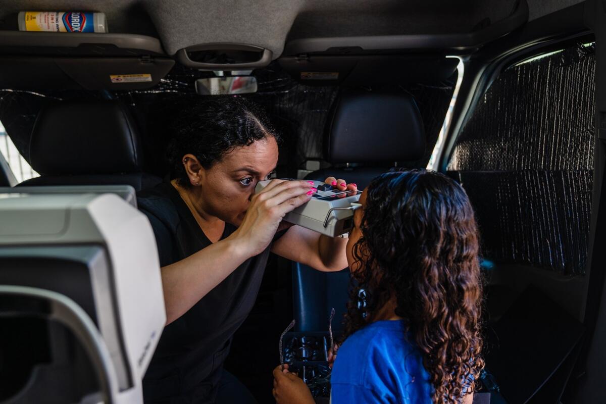 Optician Maya Ortega looks at a girl's eyes inside the Vision to Learn mobile optometry clinic