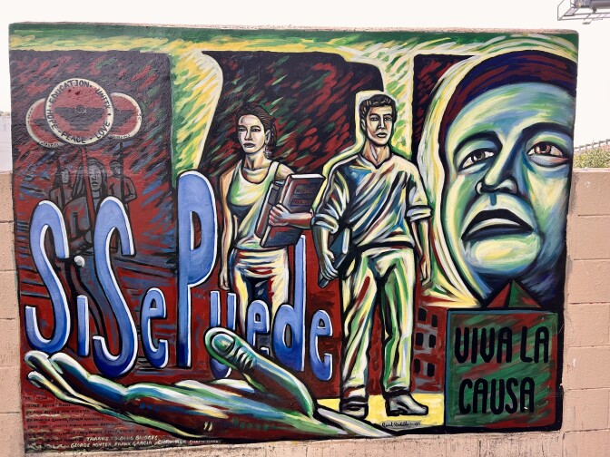 A mural depicsts two young adults holding books.