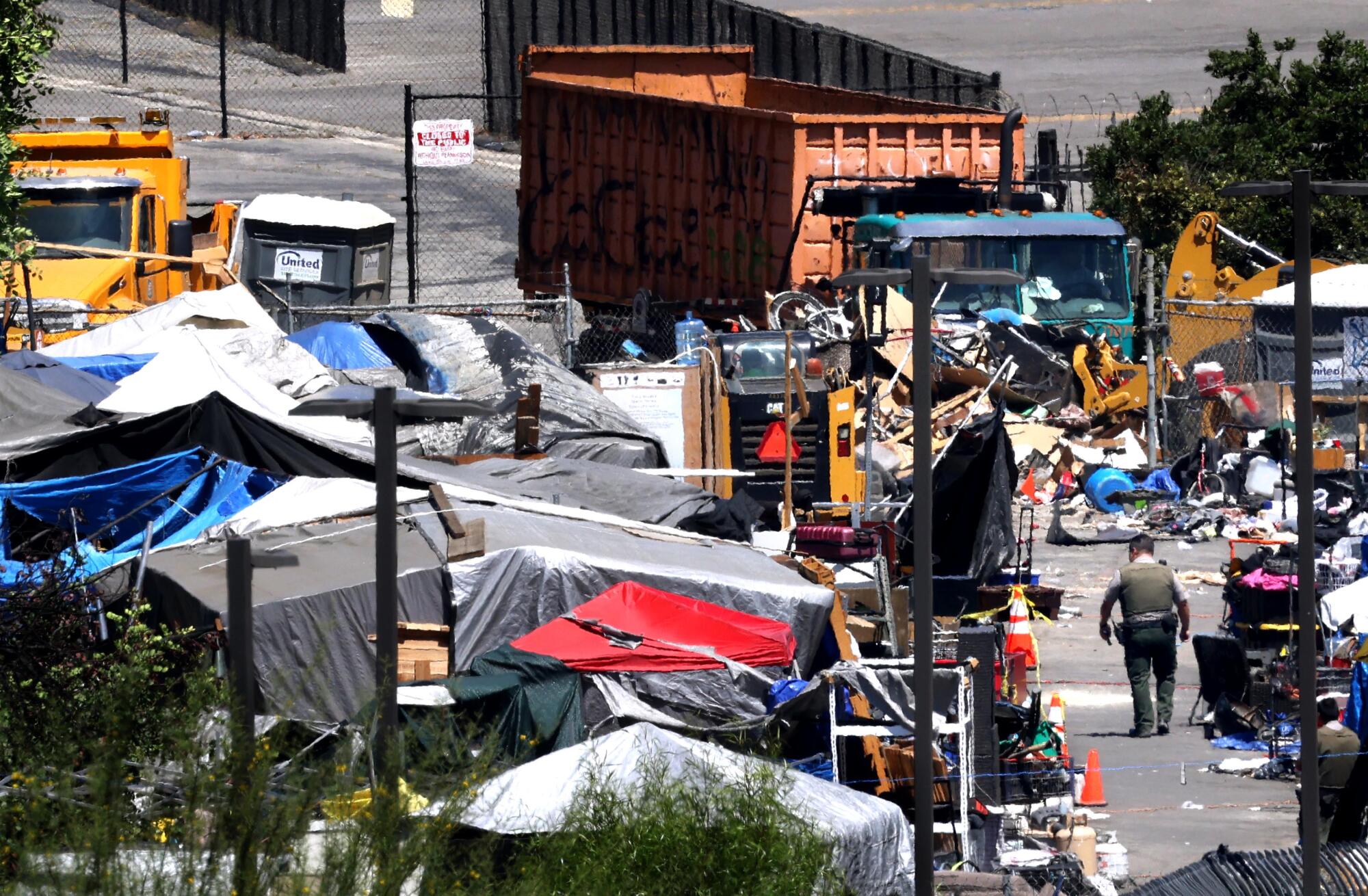 July 2025 image of an officer walking through a large homeless encampment in Van Nuys.