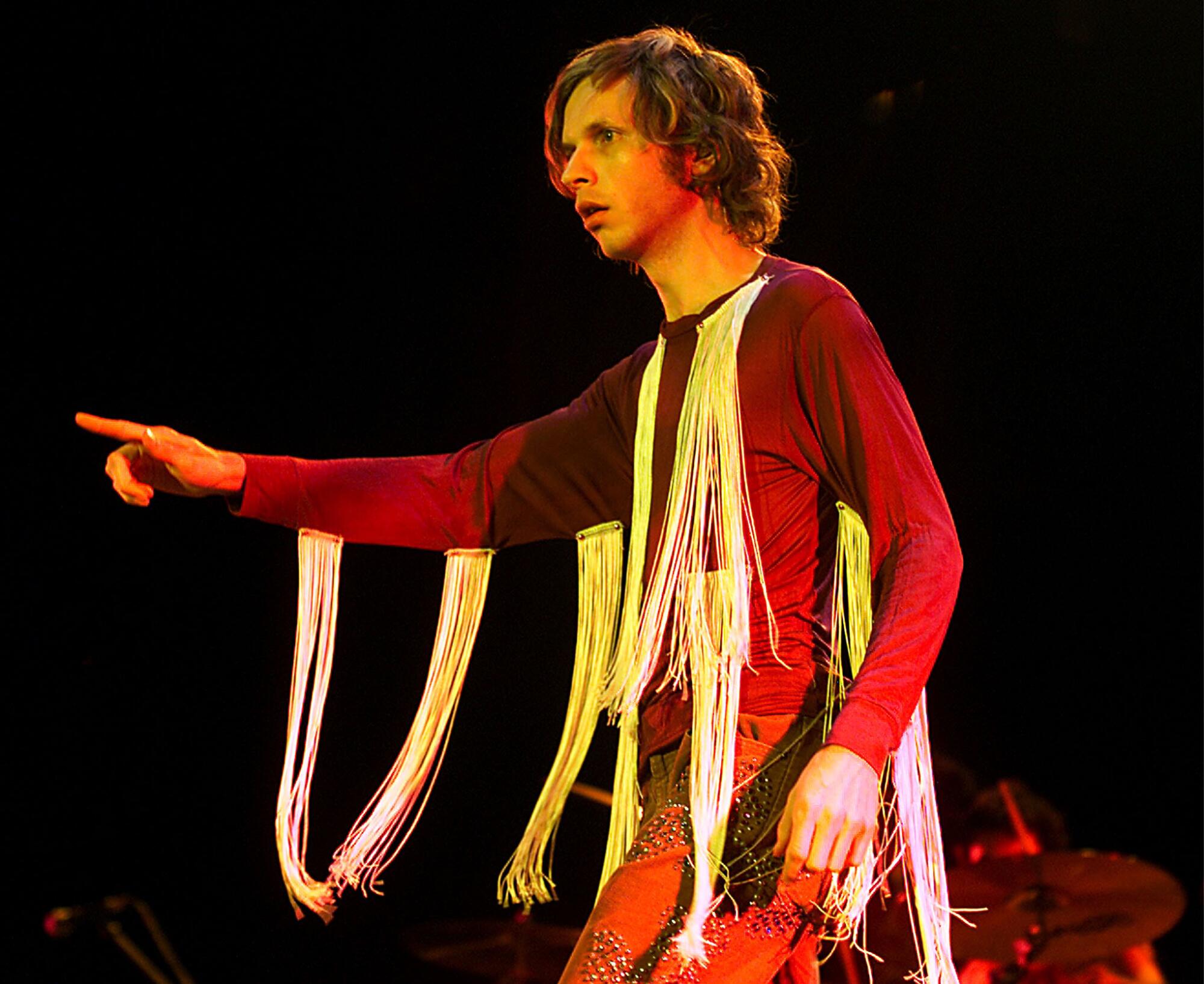 Beck on stage wearing a long-sleeved shirt covered with ribbons of fringe