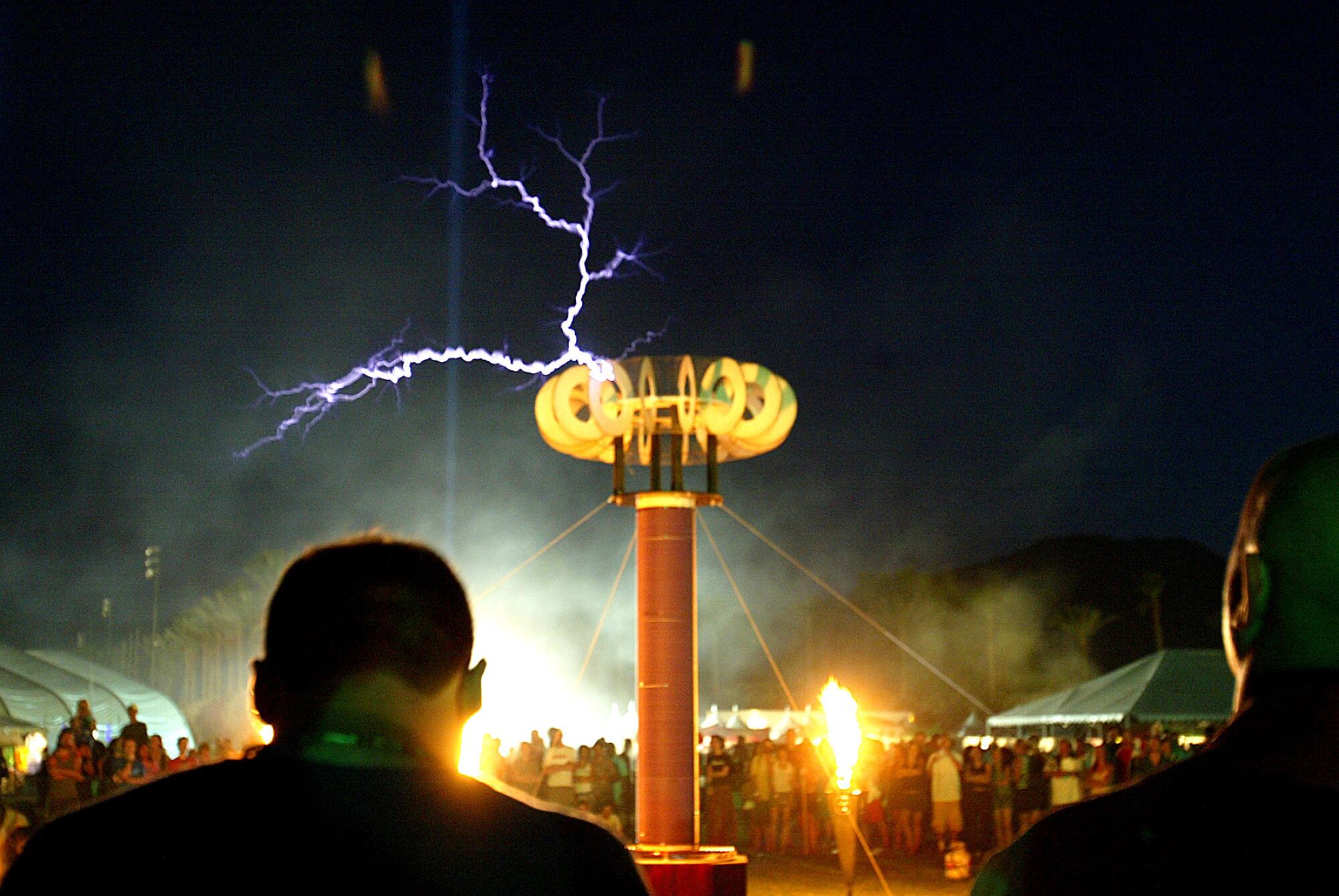 Flashes of lightning generated by a tesla coil while people stand around and watch