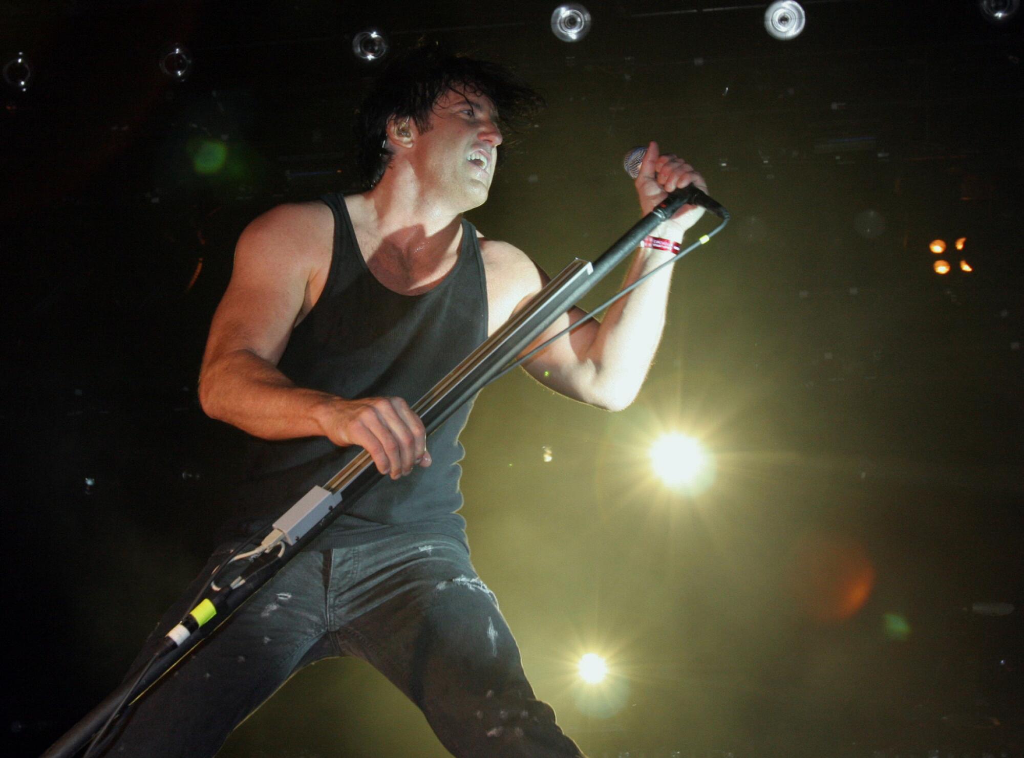 Trent Reznor of Nine Inch Nails leans with a microphone 