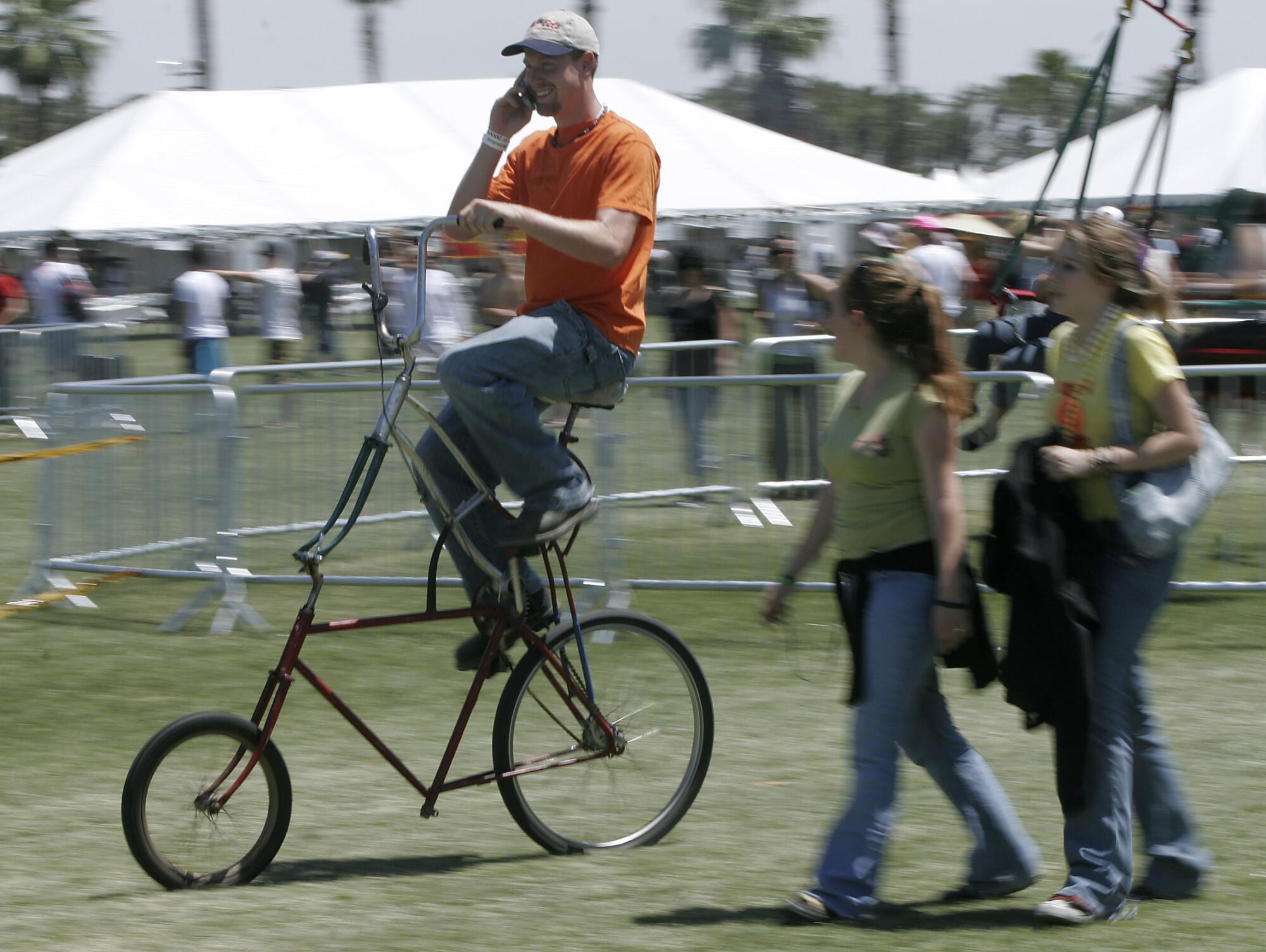 A man rides a tall bicycle in a field at Coachella