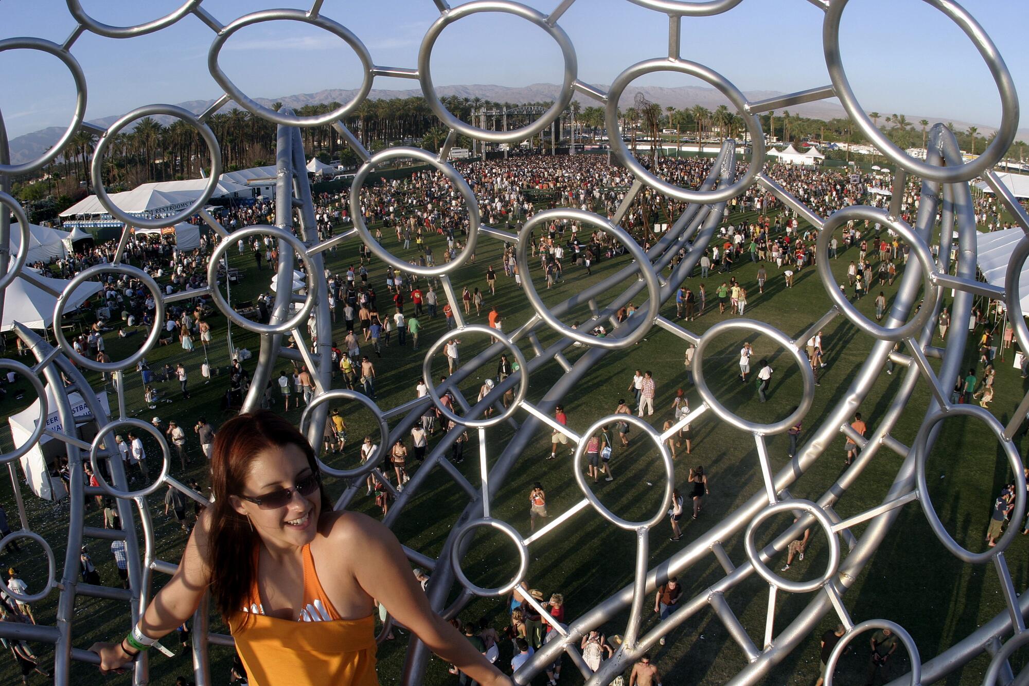 A woman in a metal structure of circles above the crowd on the field at Coachella