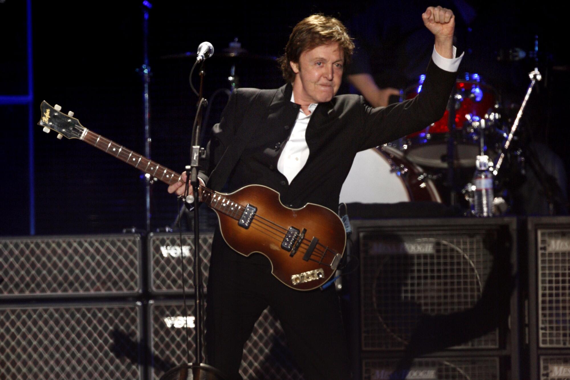 Paul McCartney on stage with his bass and a fist in the air