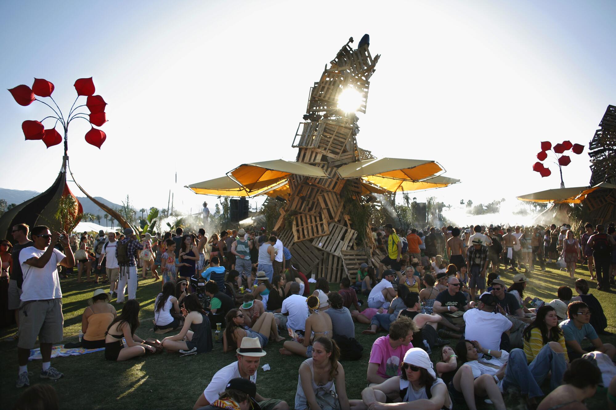 People sit around a tower of wooden pallets and catch shade