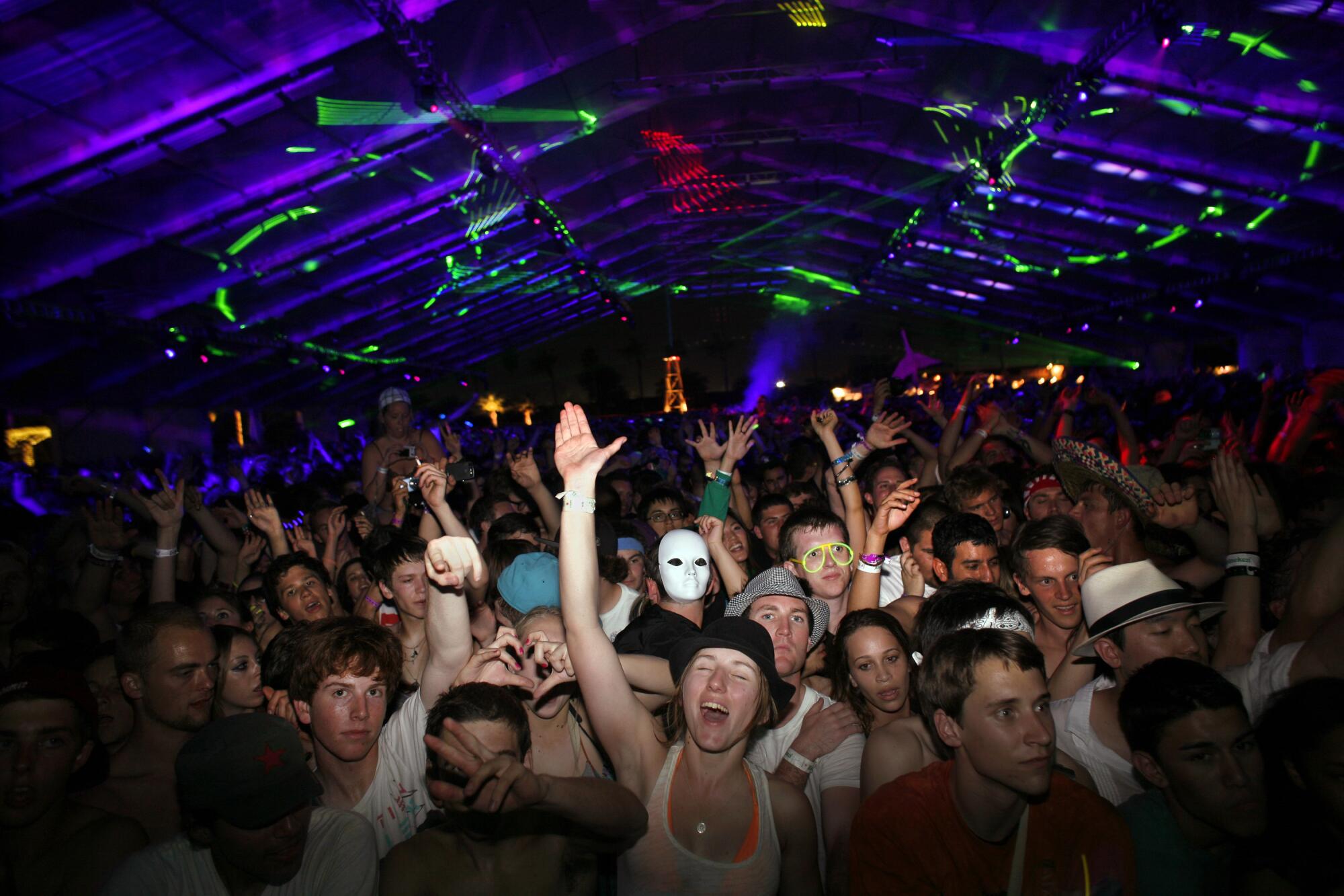 People dance and cheer inside the Sahara Tent at Coachella at night