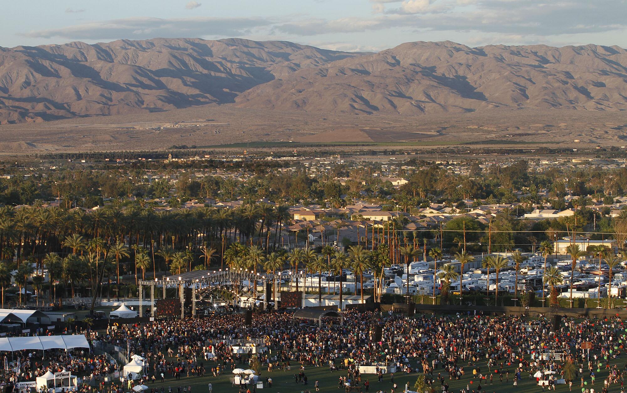 Aerial shot of the Coachella Festival with thousands of people in front of a stage with the mountains in the background