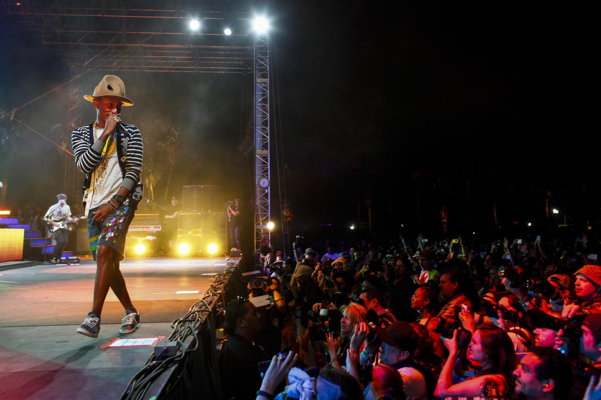  Pharell Williams performs on a stage wearing a hat