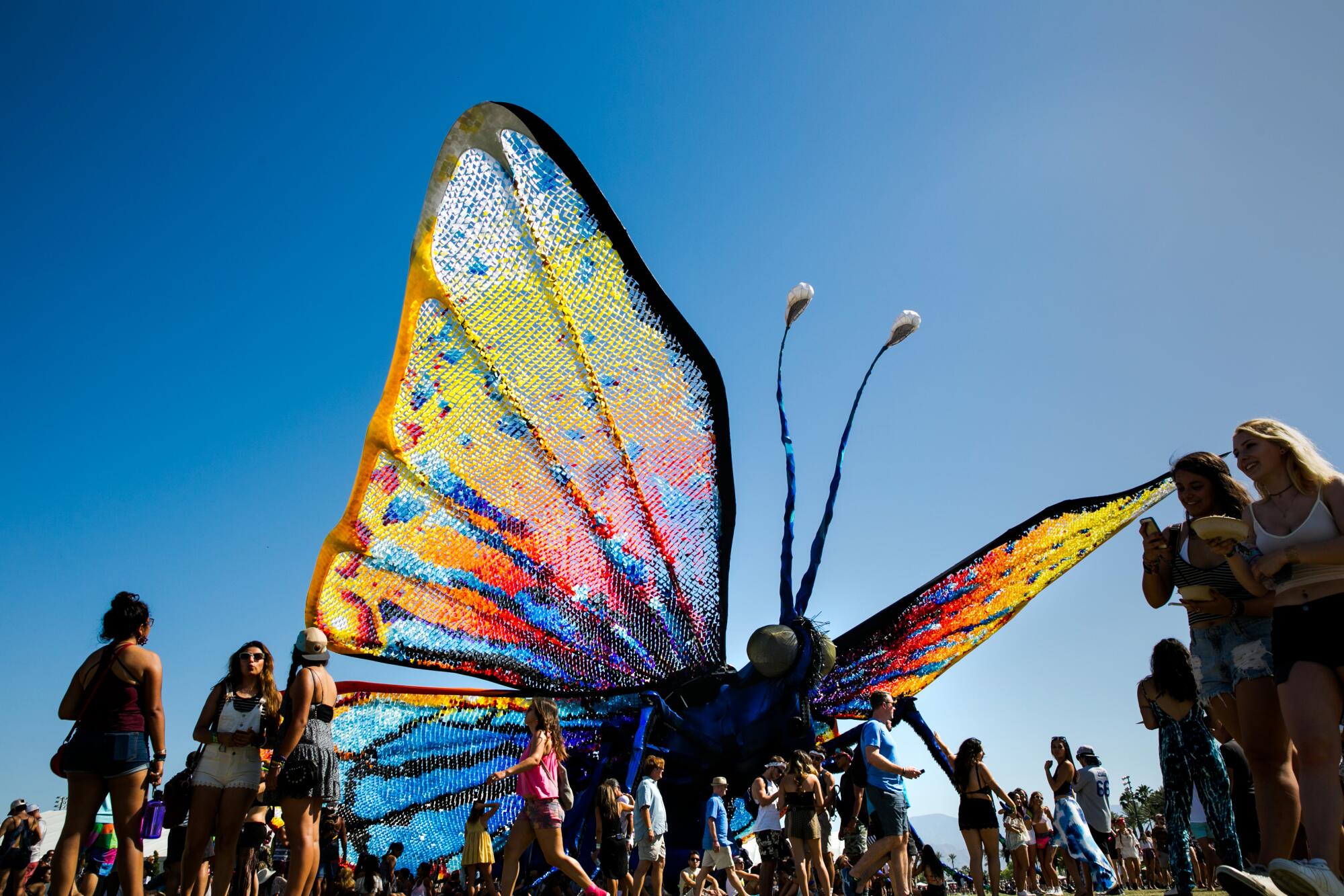 colorful butterfly sculpture surrounded by music fans at Coachella