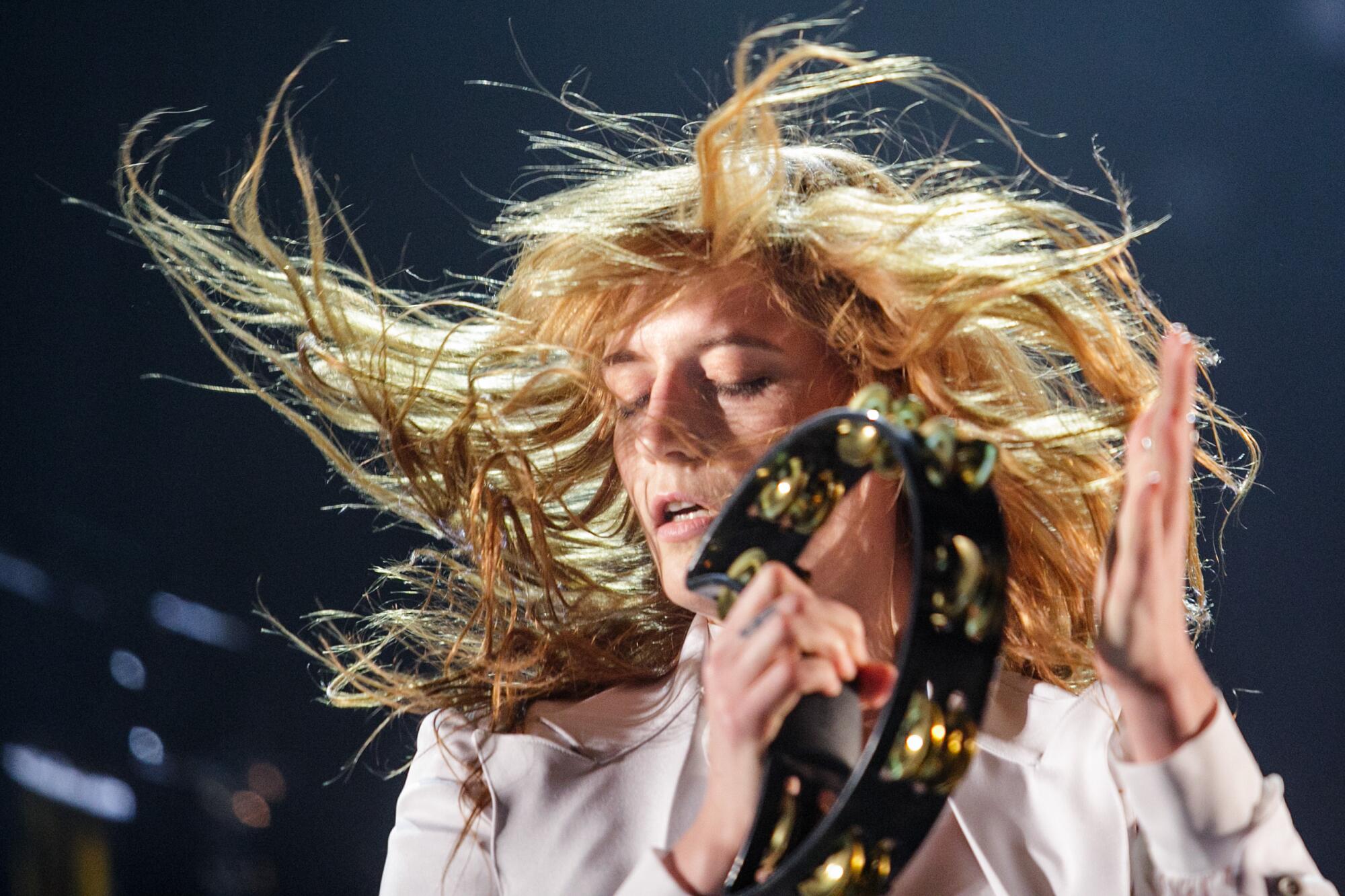 Florence Welch's hair swirls around her as she hits a tambourine