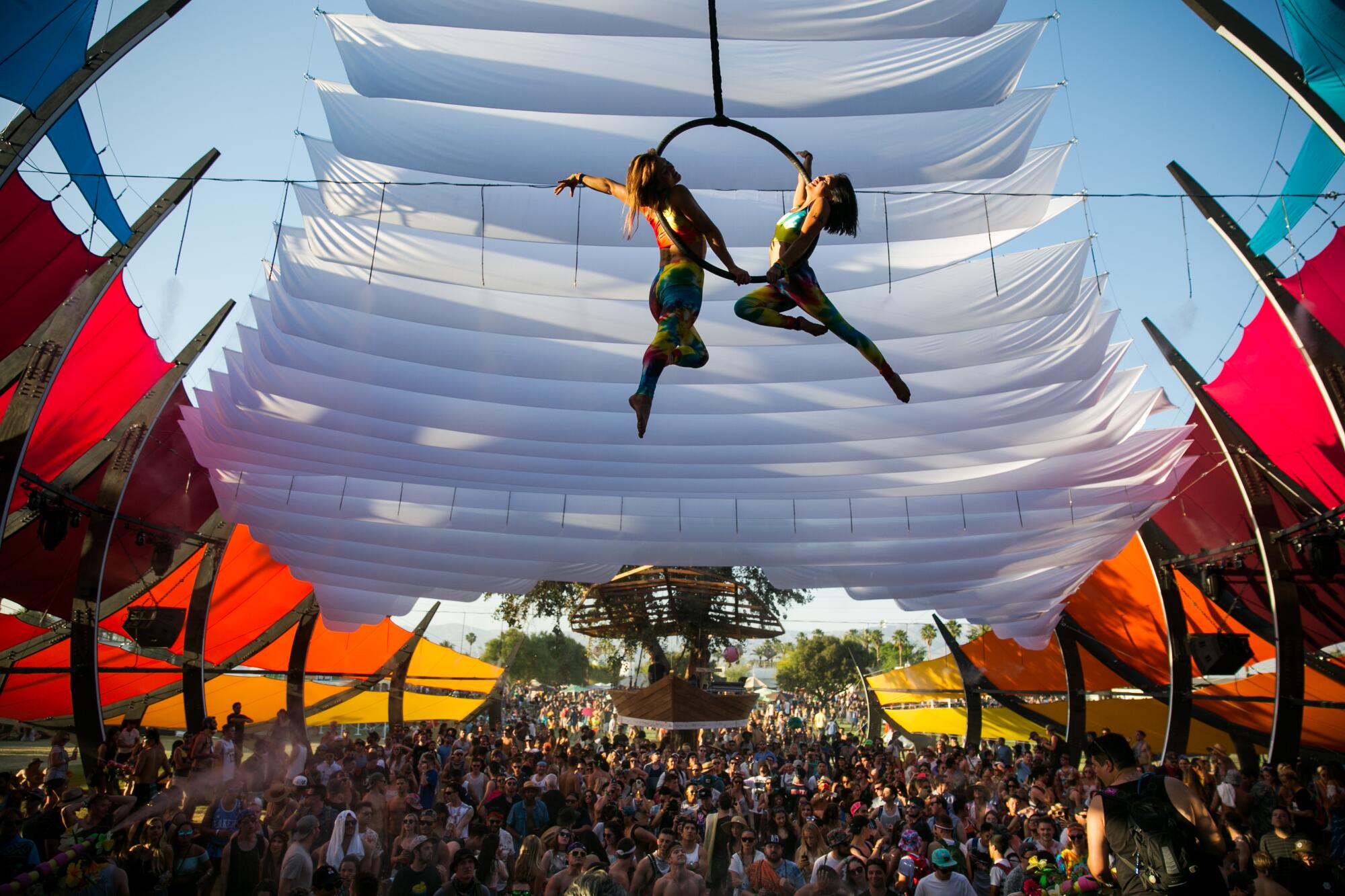 Aerial performers on a hoop above thousands of fans under a colorful tent