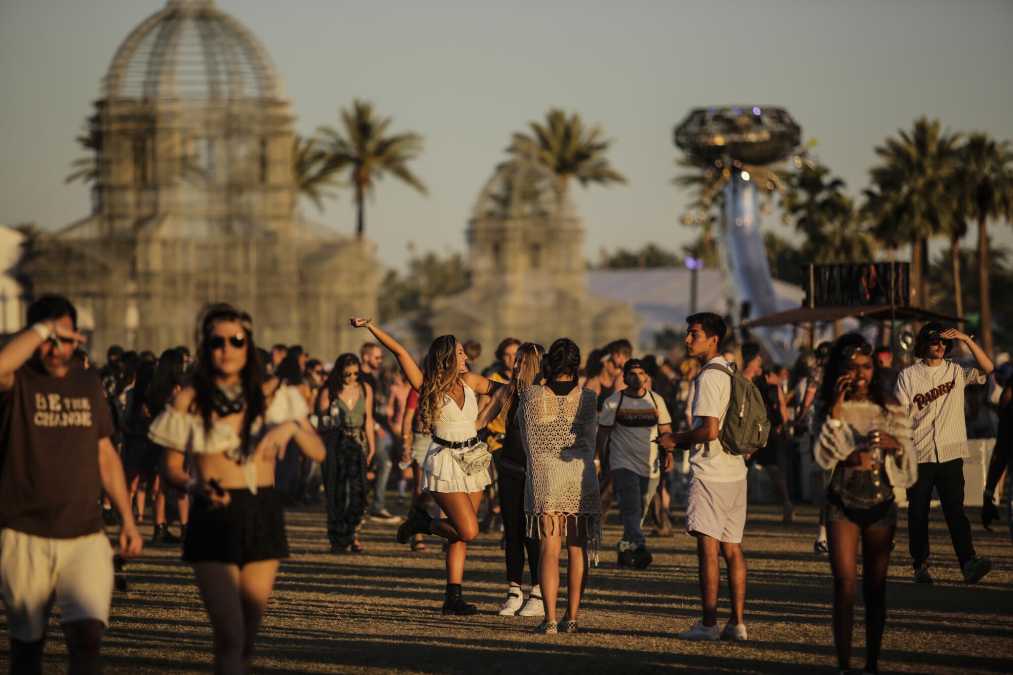 People walk by metal sculptures at dusk with palm trees in the background