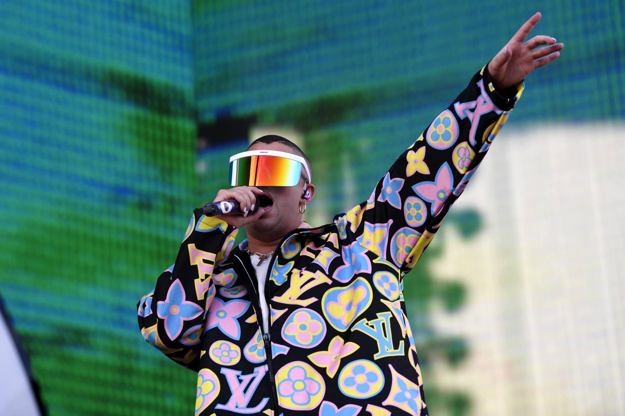 Bad Bunny wears colorful visor sunglasses and a colorful shirt while performing