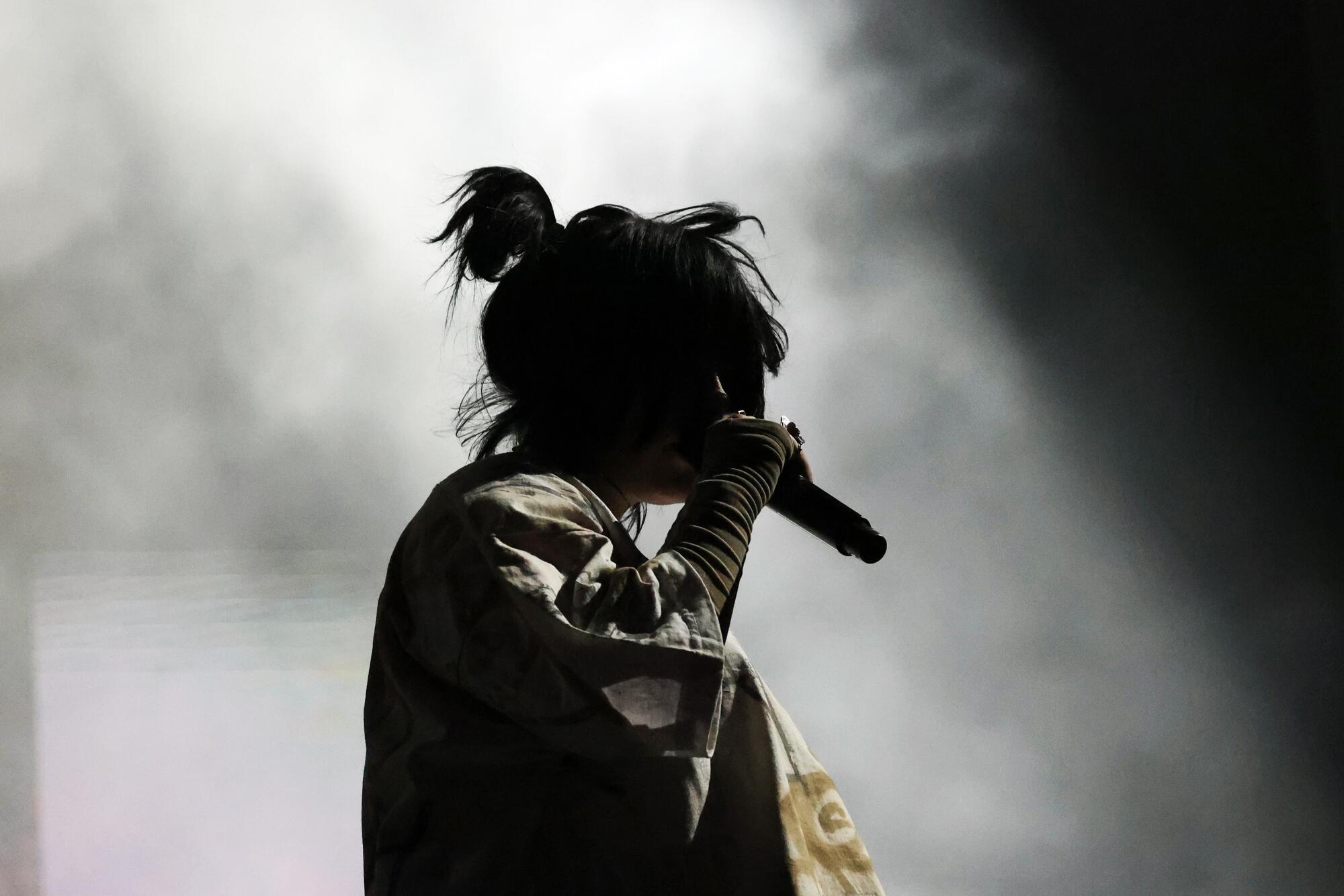 Silhouette of Billie Eilish holding a microphone