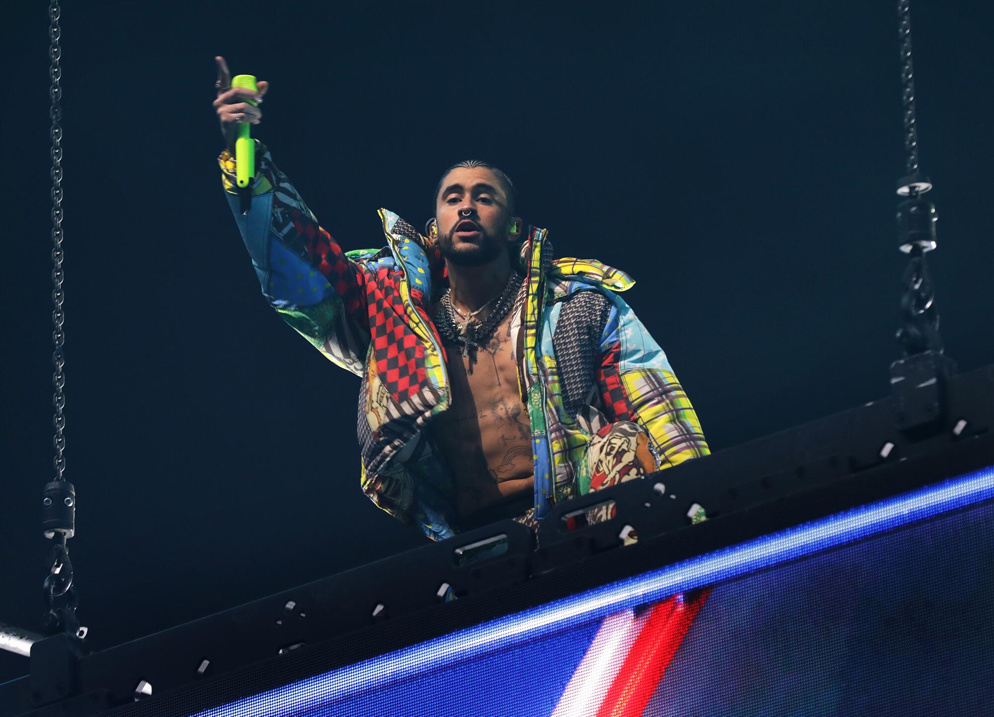 Bad Bunny holds a microphone in the air