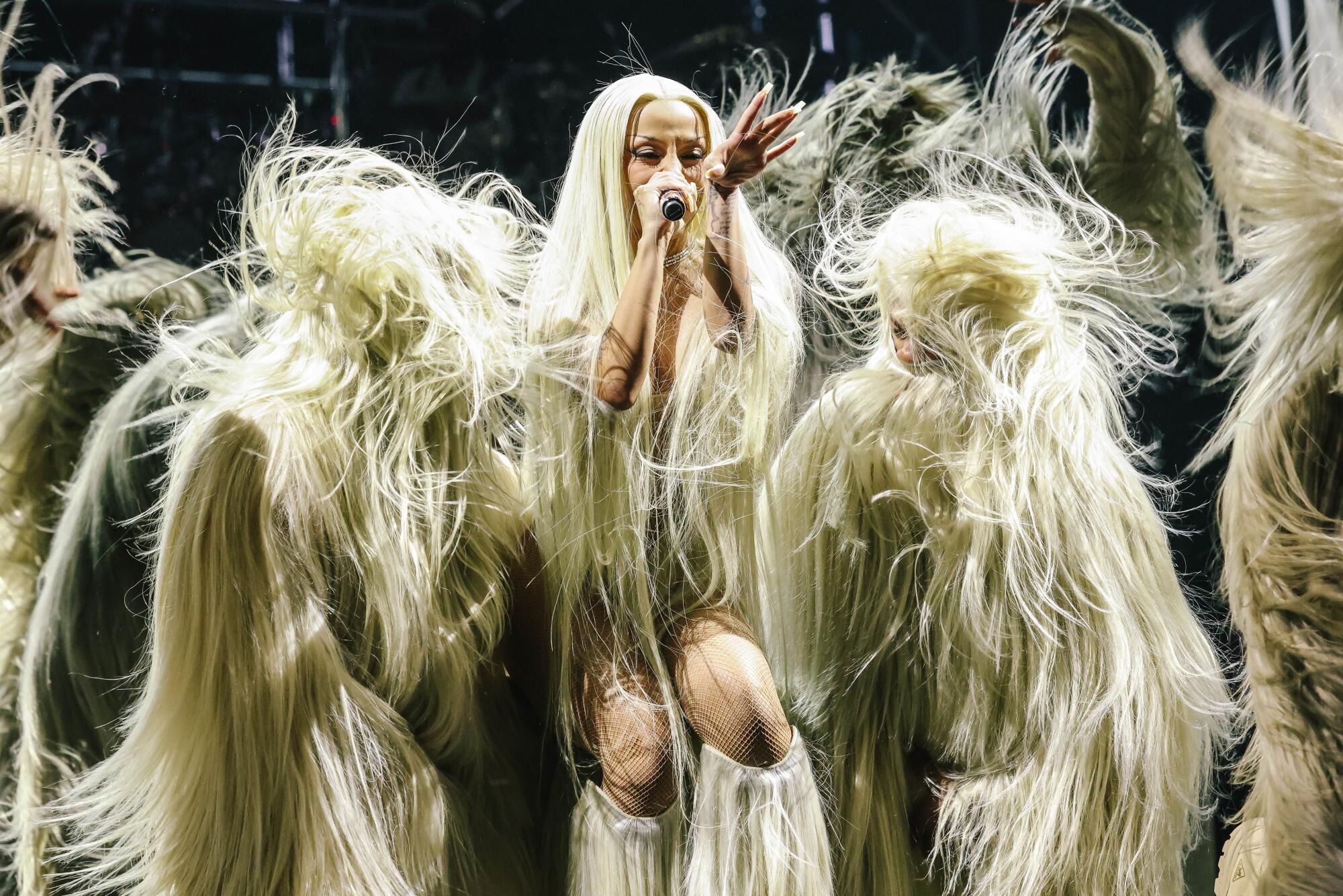  Doja Cat sings into a microphone while surrounded by yetis