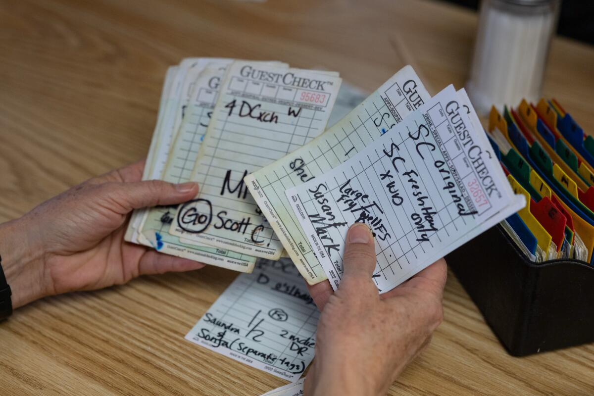 Julie Malik, a Damburger co-owner, flips through old order tabs for loyal customers.