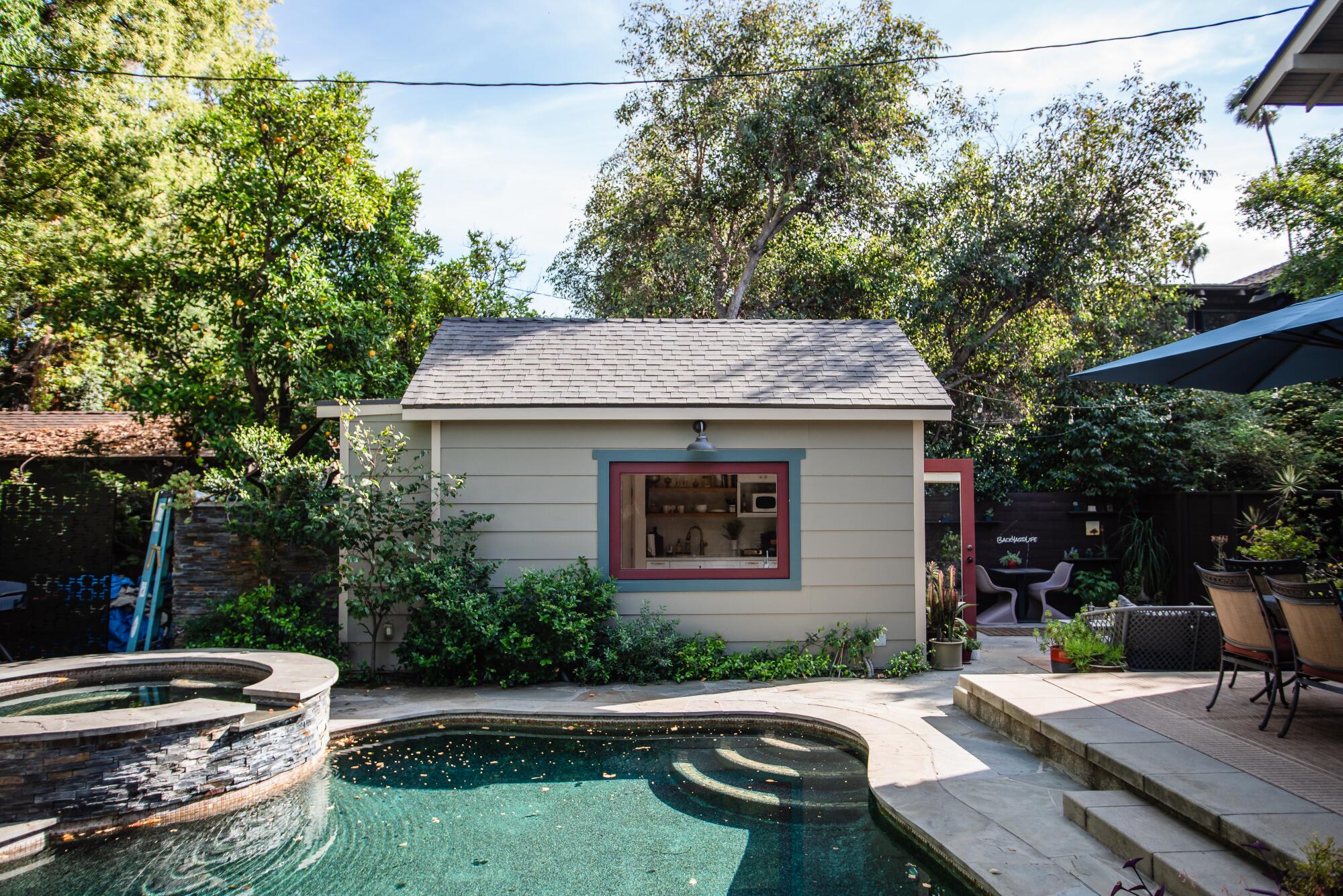 A Craftsman style ADU rests behind a swimming pool.