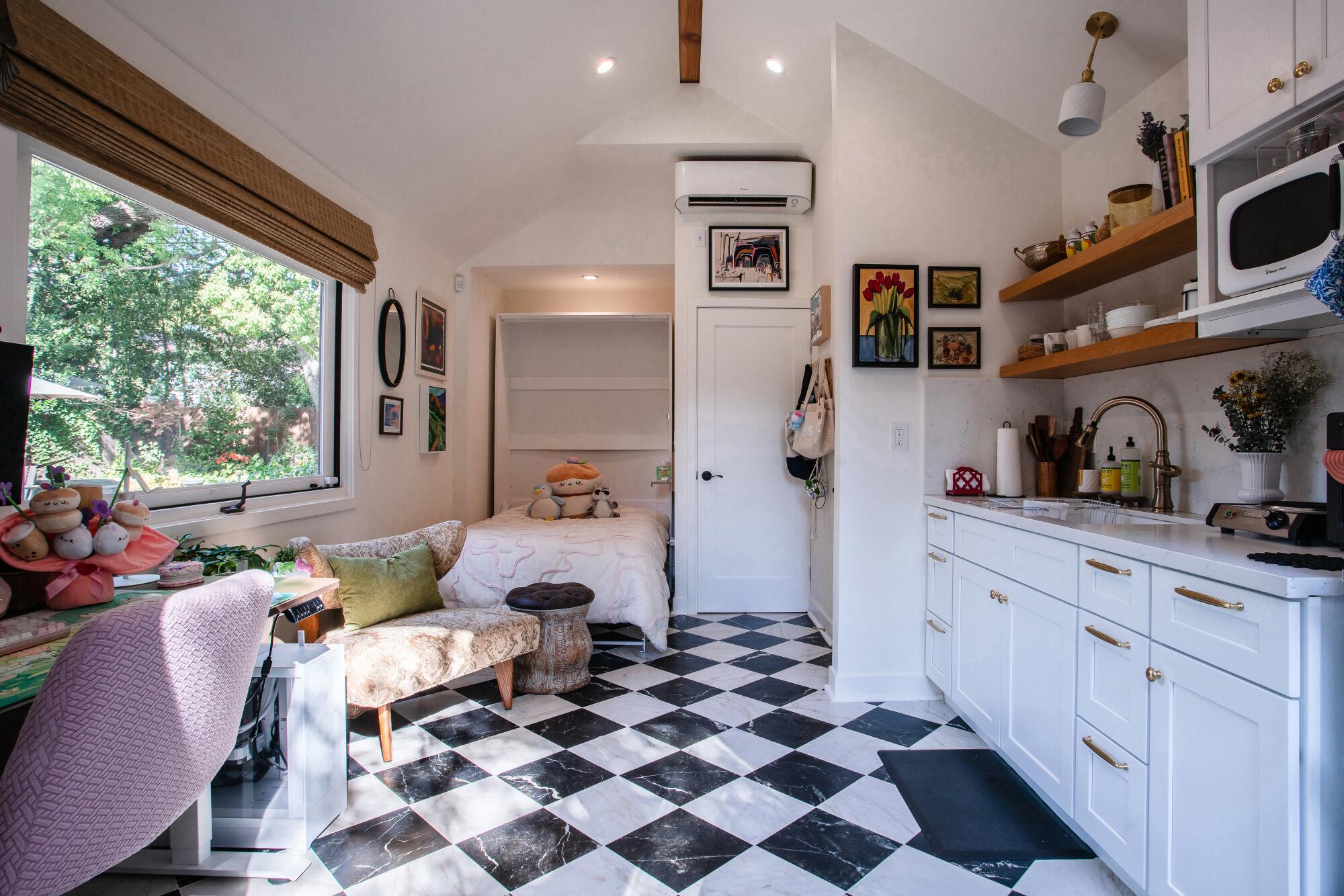 A tiny ADU with black and white tile and white kitchen.