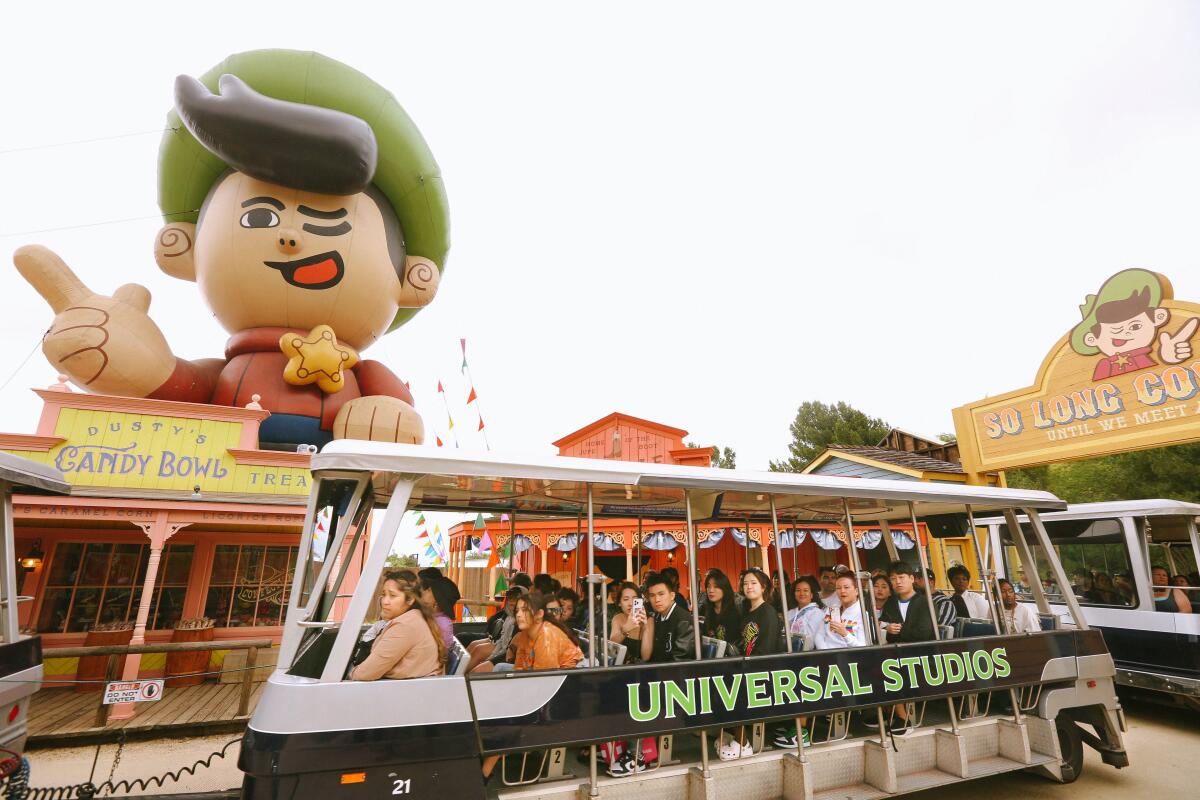 An open tram full of people next to a giant cartoon figure.