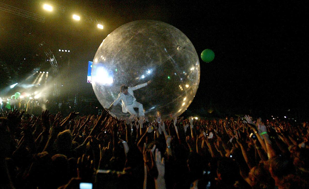 A man in a giant bubble over a crowd.