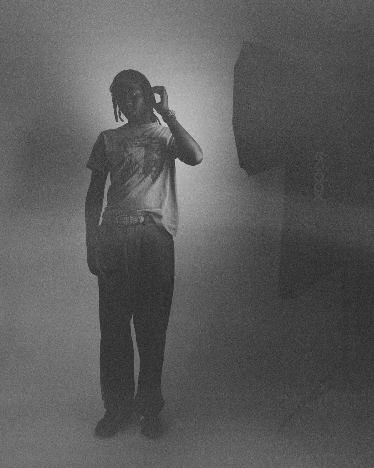 Devonte Hynes, known as Blood Orange, stands while wearing a white t-shirt and slim jeans.