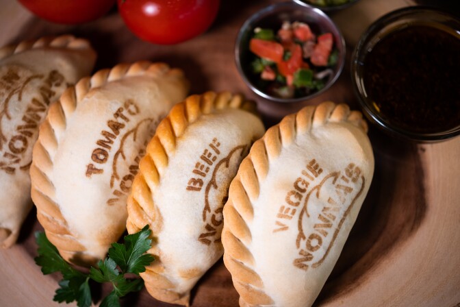 Three light colored empanadas, with each one saying tomato, beef and veggie, and the Nonna's logo.