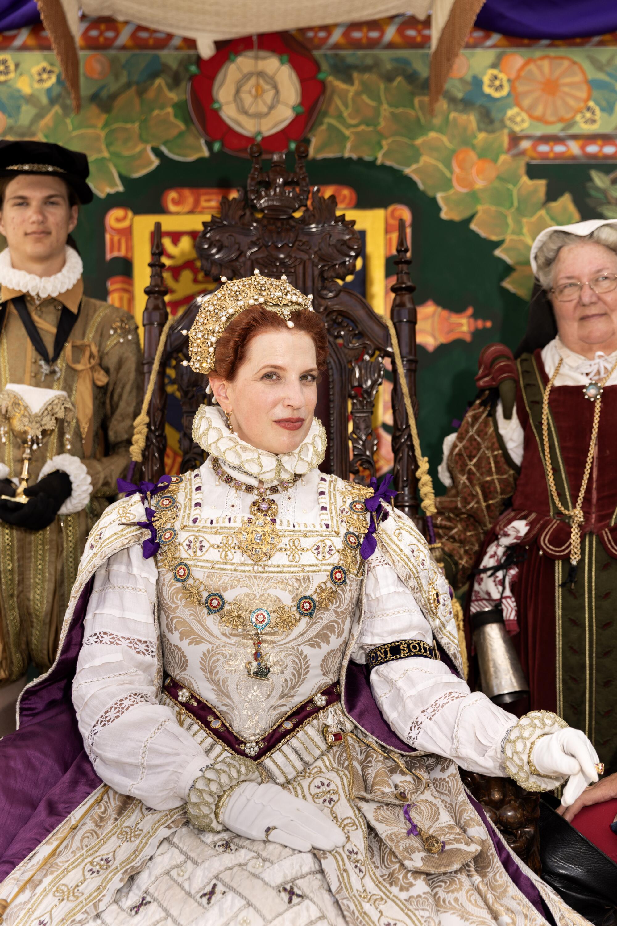 A regal redhead with a gold crown in a corset style gown with gold and cream adornments