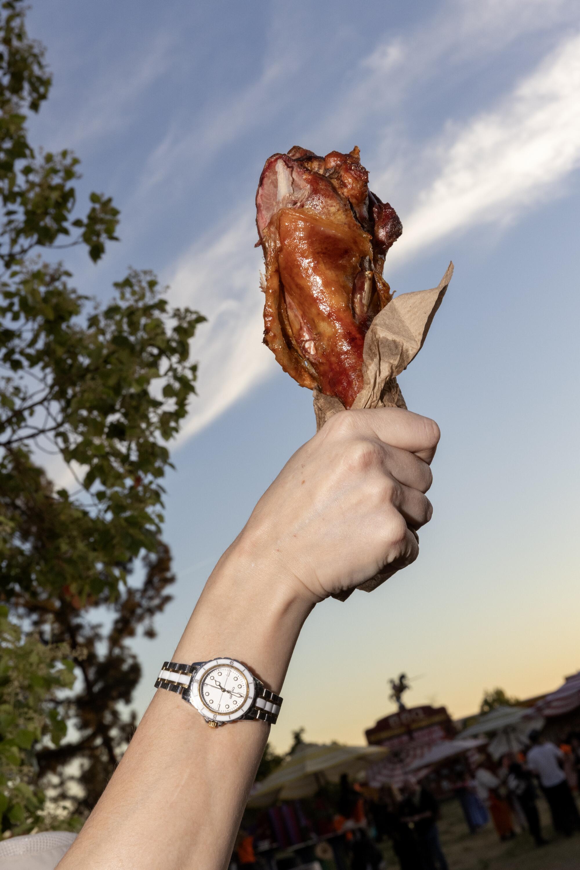 A person holds up a red hunk of meat