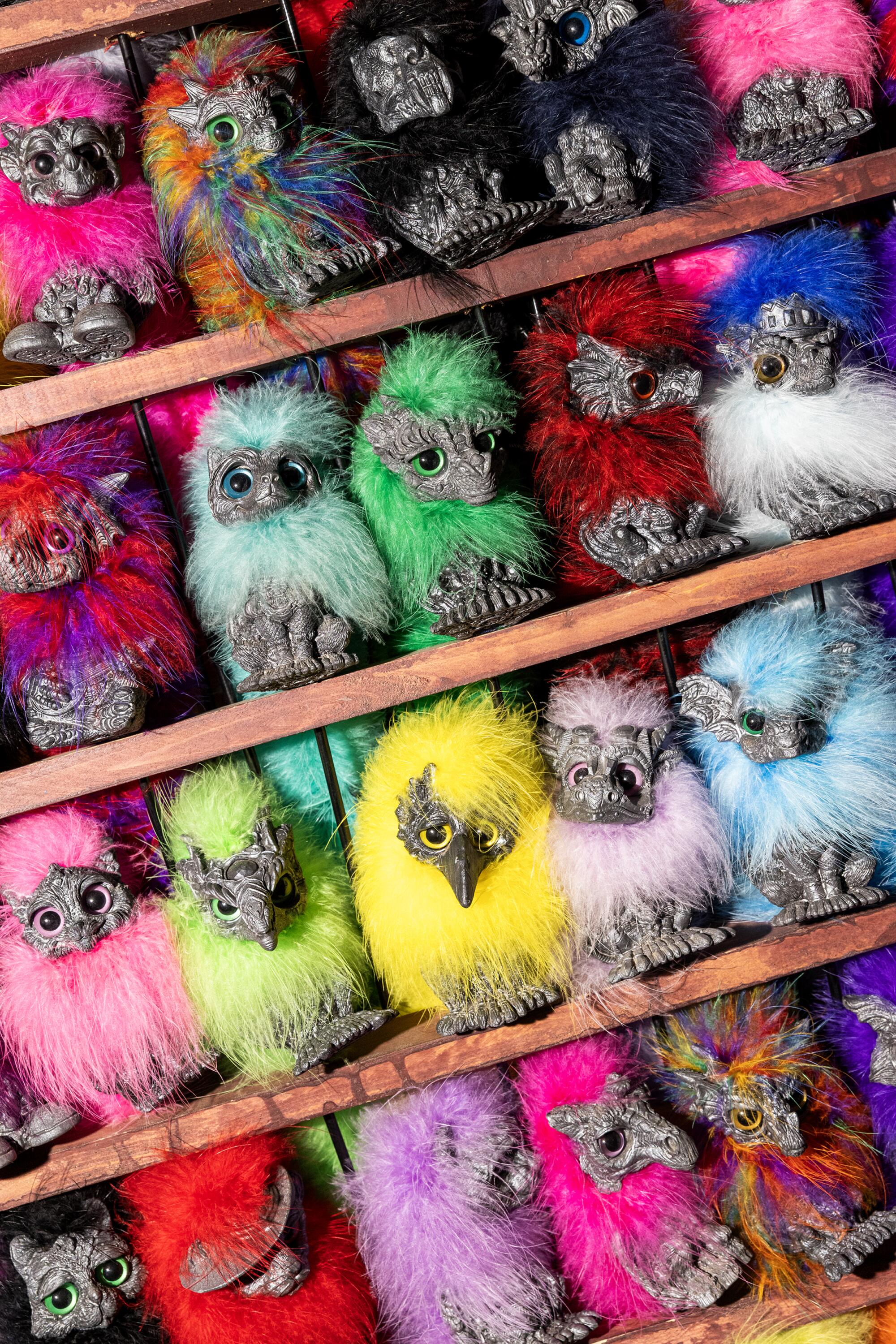 several brightly colored dragon-inspired puppies line a wooden shelf