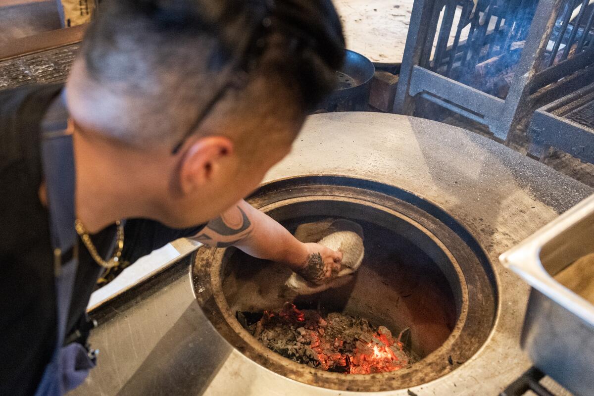 LOS ANGELES, CA - APRIL 01 2026: Josh Sta Ana, chef de cuisine at Maydan Restaurant, makes tone bread in a wood-fired oven on Wednesday, April 1, 2026. 