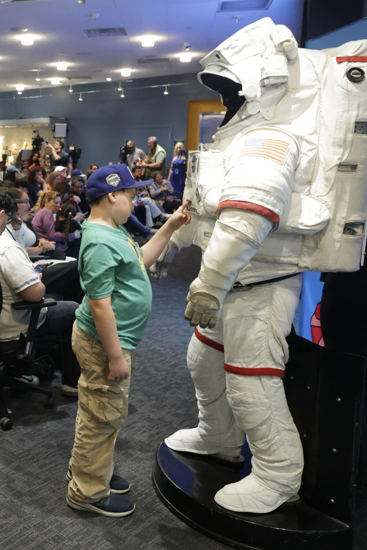 a boy checks out an astronaut suit while waiting for the Artemis II Landing Watch Party