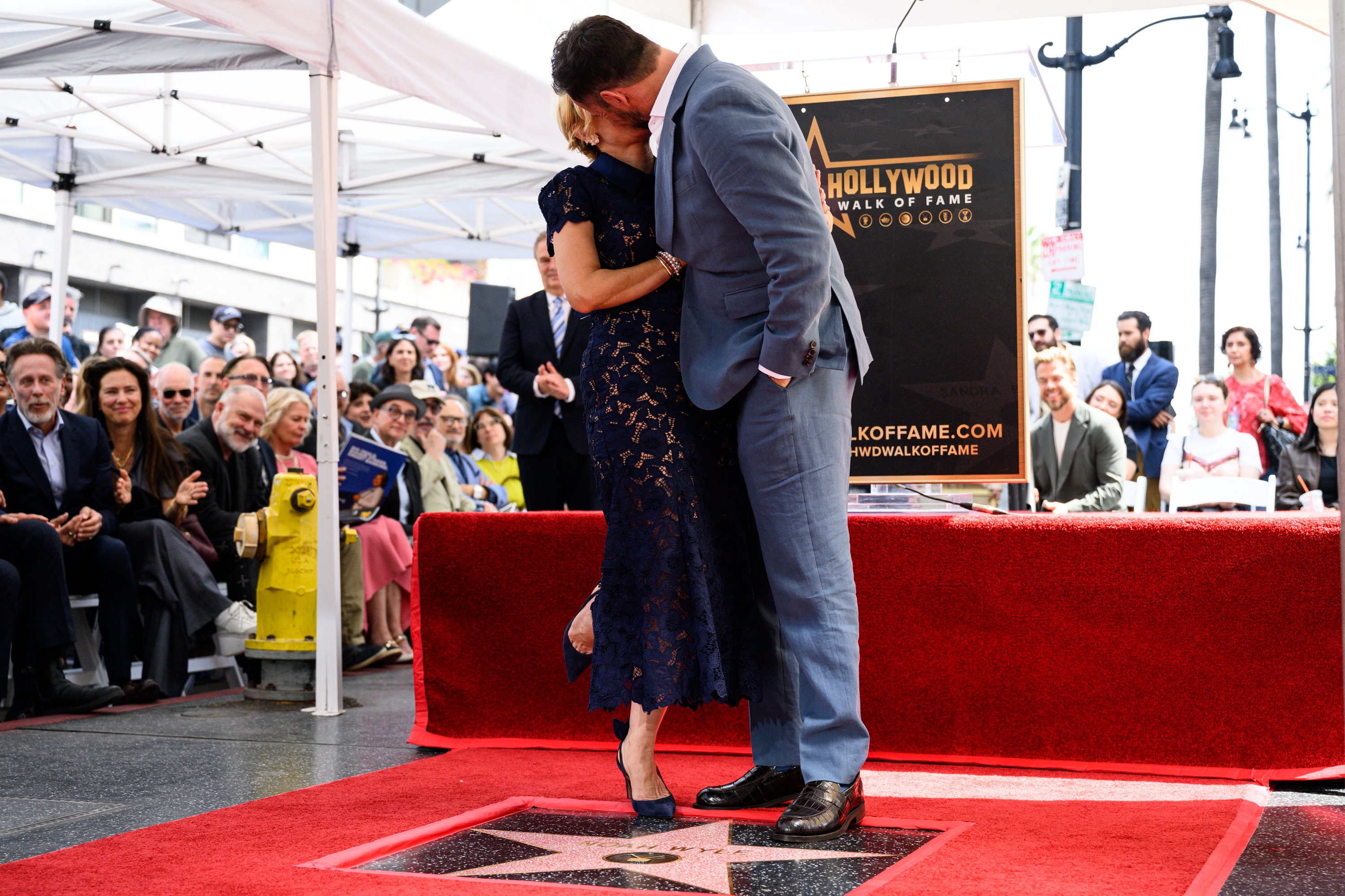 Noah Wyle and his wife Sara Wyle kiss over his...