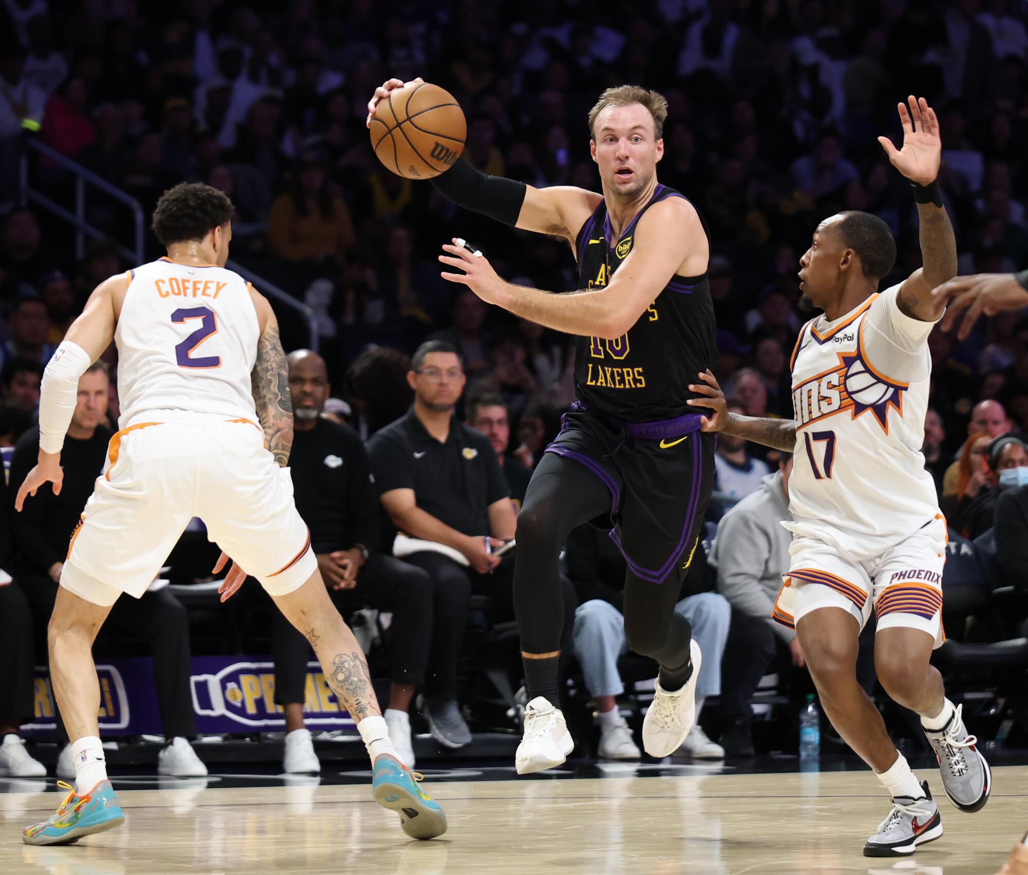 Lakers guard Luke Kennard, center, controls the ball in front of Phoenix guards Amir Coffey, left, and Jamaree Bouyea.