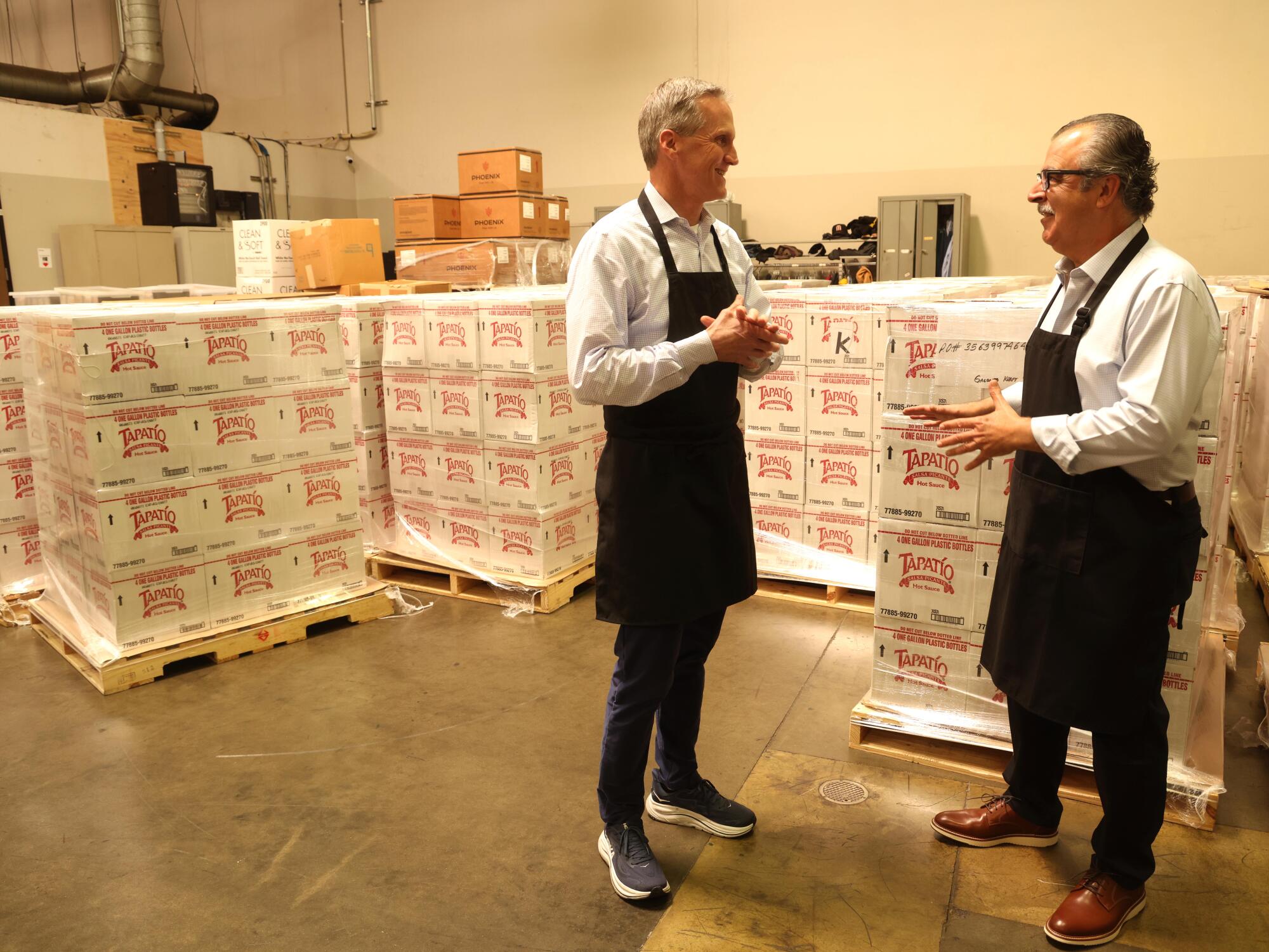 Luis Saavedra speaks with Eric Beatty near pallets of cases.