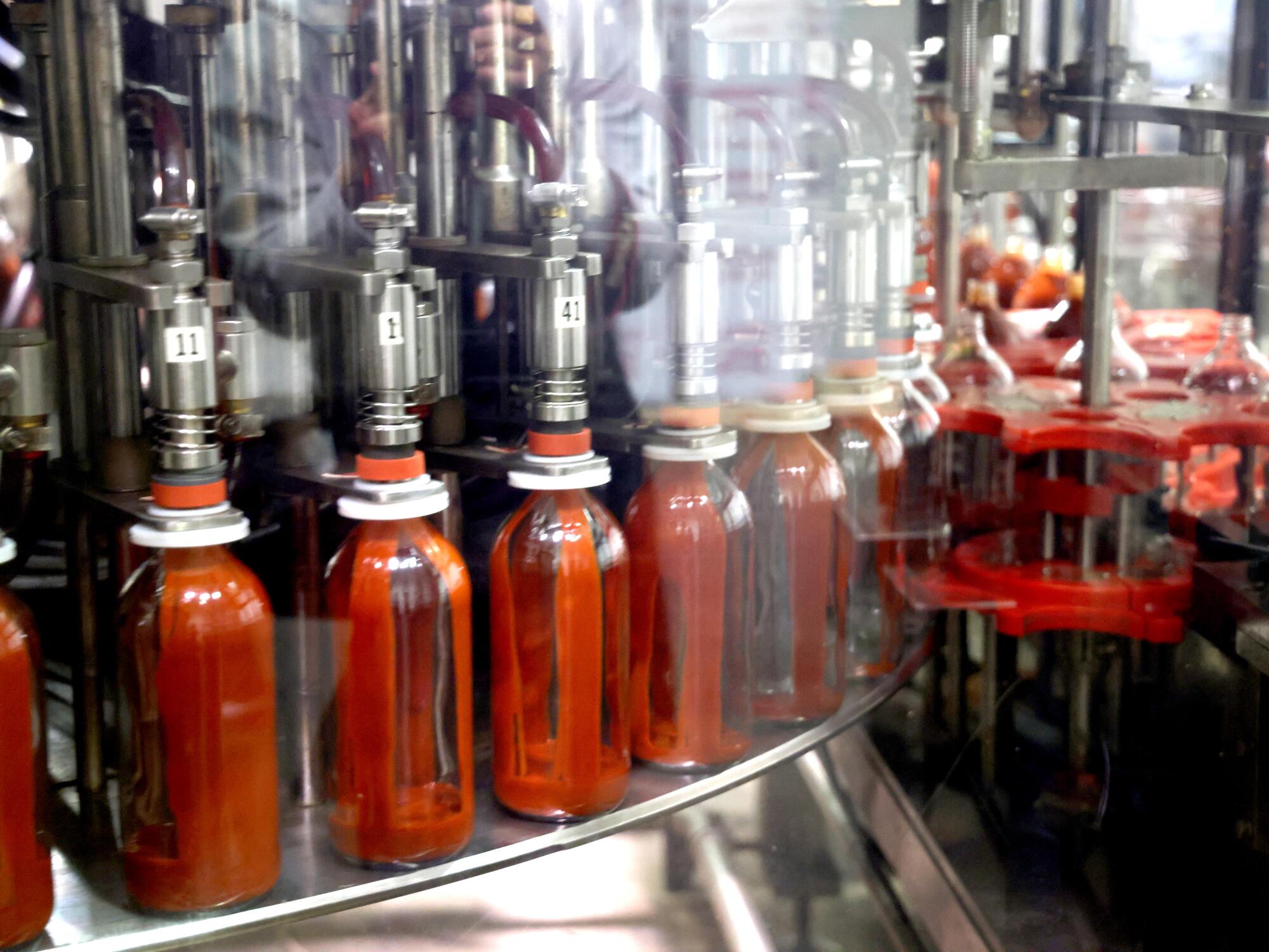 Bottles are filled with Tapatio hot sauce.